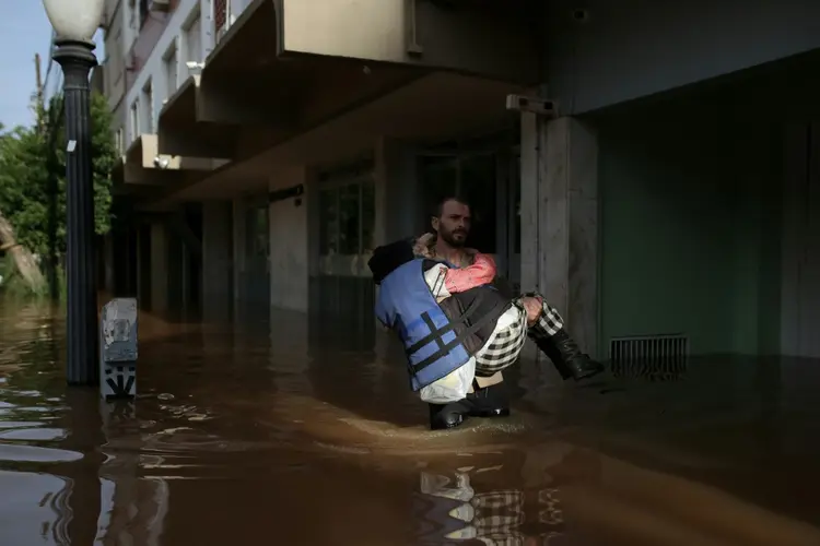 Brasil: voluntário leva uma senhora, de 79 anos, por uma rua inundada no bairro Cidade Baixa, em Porto Alegre (AFP Photo)