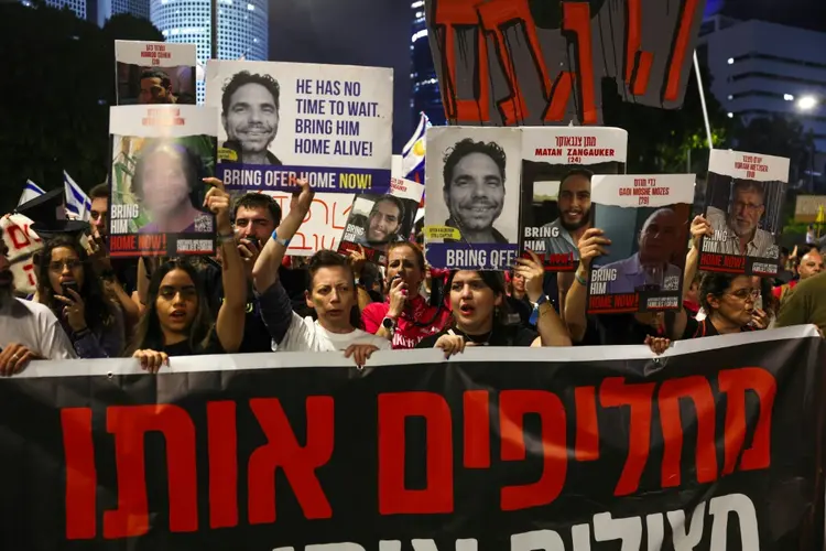 Milhares de pessoas seguram fotos de reféns em manifestação em Tel Aviv. (AFP/AFP)