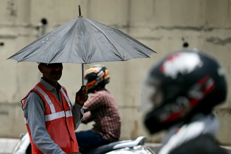 Enquanto os países em desenvolvimento pedem aumentos na ajuda climática, um funcionário de uma cabine de pedágio se protege sob um guarda-chuva durante uma onda de calor recorde em Nova Délhi (AFP Photo)