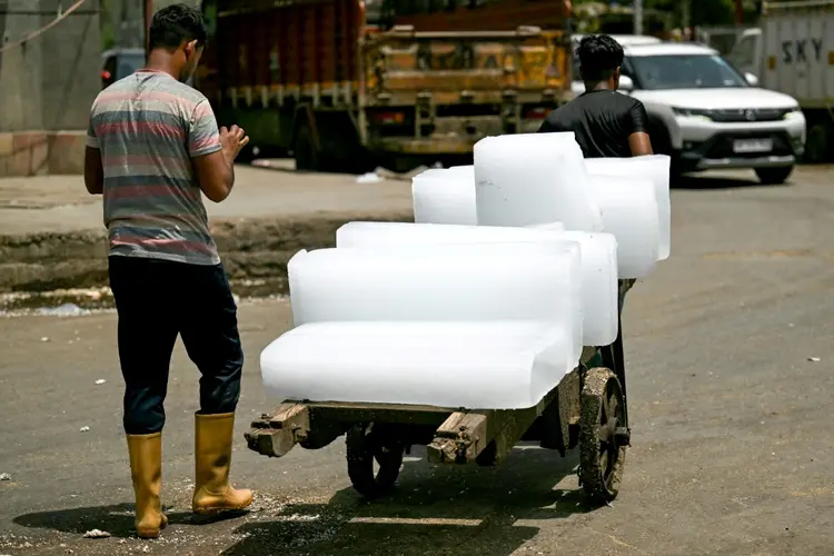 Dois trabalhadores transportam blocos de gelo em uma carroça em Nova Délhi (AFP/AFP)