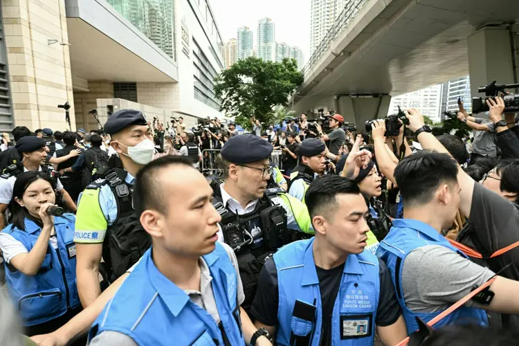 Policiais tentam controlar a imprensa do lado de fora do tribunal de West Kowloon, na cidade semiautônoma chinesa de Hong Kong. (AFP/AFP)