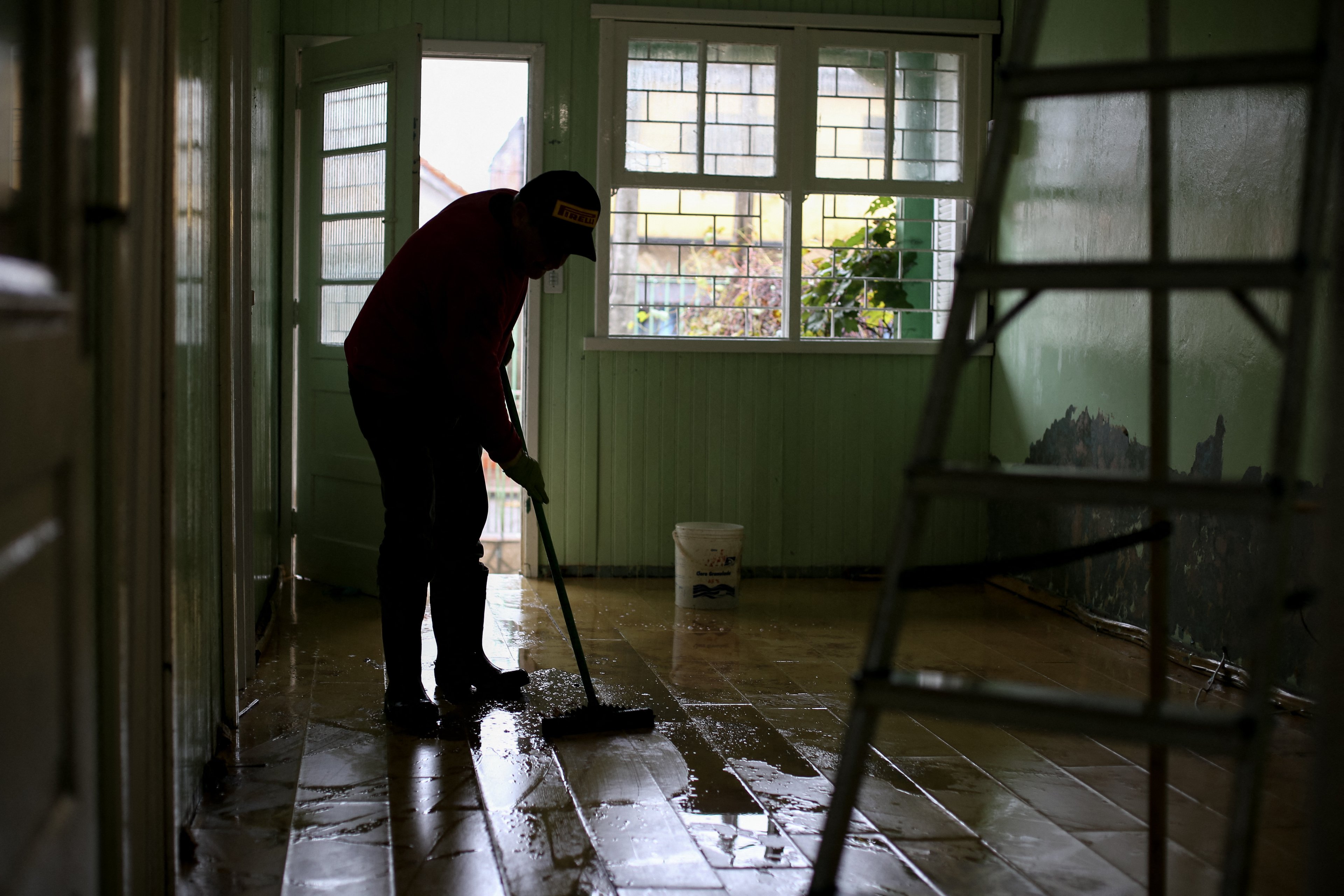 Um homem limpa sua casa atingida pela enchente no bairro Sarandi