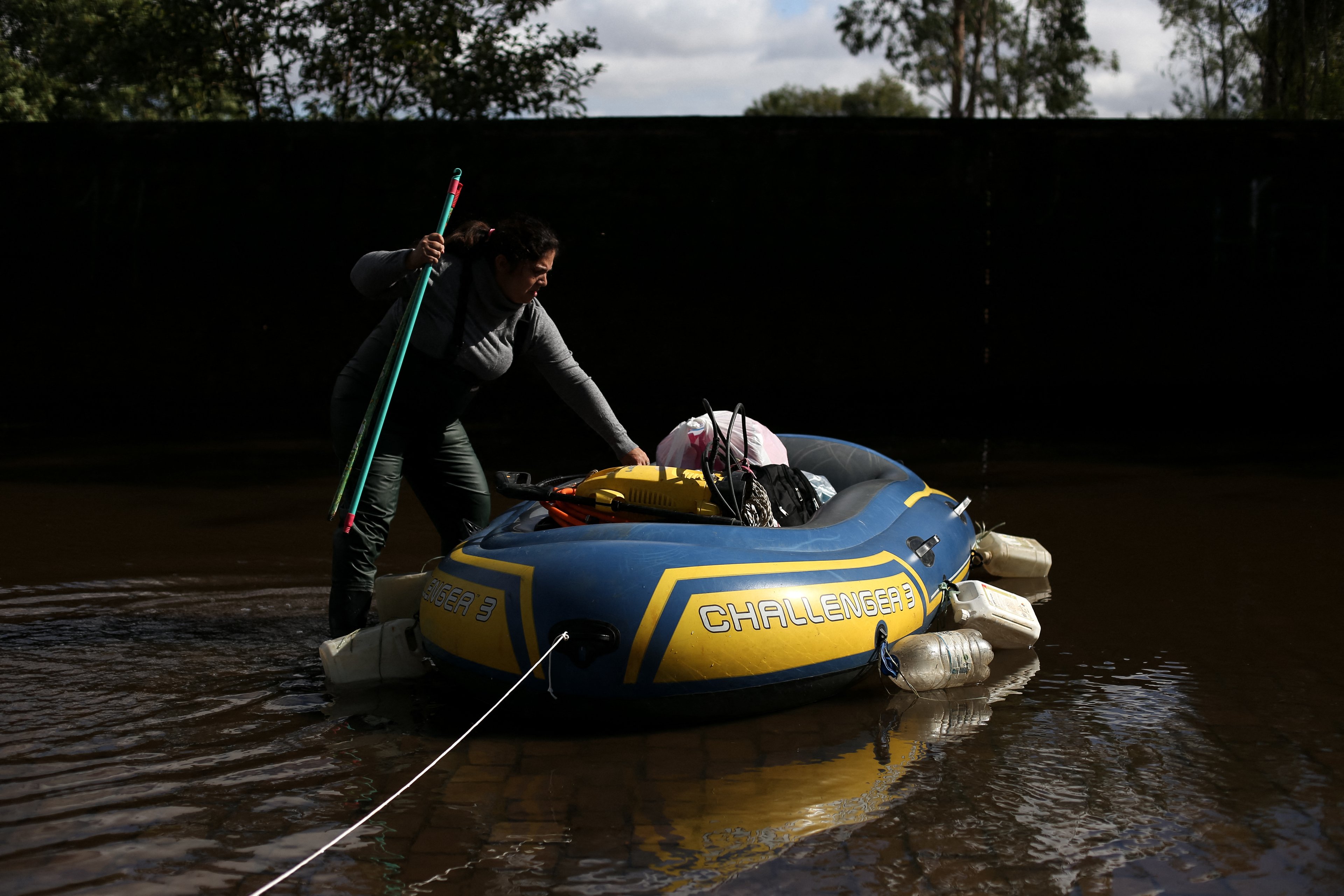 Ana Emilia Faleiro usa um barco para transportar suprimentos em uma rua inundada em Porto Alegre