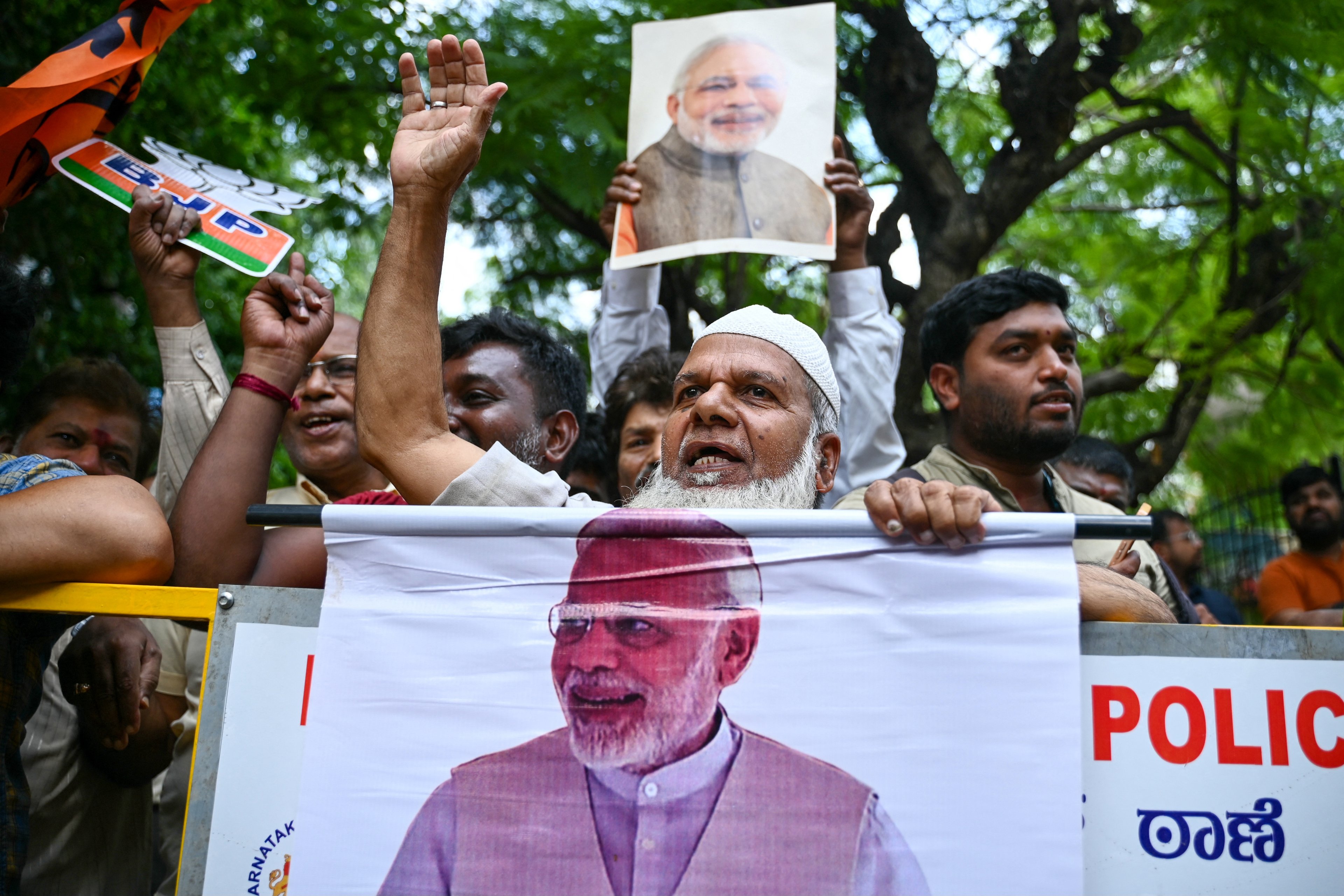 Apoiadores de Narendra Modi, Primeiro-Ministro da Índia e líder do Partido Bharatiya Janata (BJP), seguram seus retratos enquanto comemoram os resultados da contagem de votos das eleições gerais da Índia, do lado de fora de um centro de contagem em Bengaluru, em 4 de junho de 2024. O Partido Bharatiya Janata (BJP) do Primeiro-Ministro Narendra Modi estava em primeiro lugar com 38,1 por cento dos votos contados nas eleições da Índia, de acordo com dados da comissão eleitoral nacional divulgados em 4 de junho. (Foto por Idrees MOHAMMED / AFP)