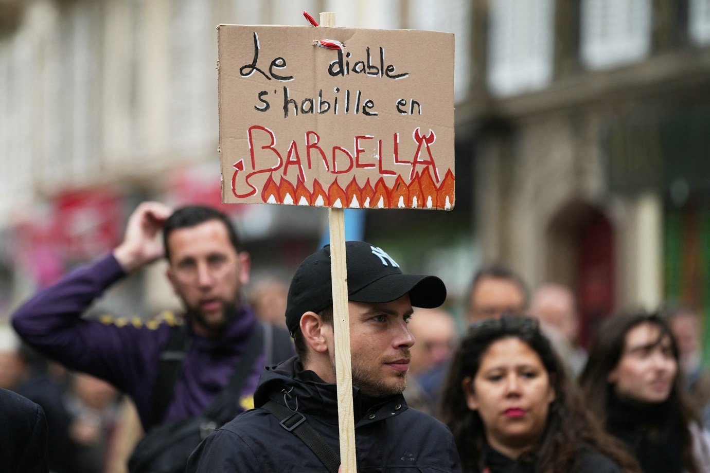A demonstrator holds a placard reading "The devil wears Bardella" during an anti far-right rally after French president called legislative elections following far-right parties' significant gains in European Parliament elections, in Paris on June 15, 2024. Less than a week after the earthquake of the dissolution, opponents of the far-right are called by trade unions, associations and the left-wing coalition of the "Nouveau Front Populaire" to take to the streets across France. (Photo by Zakaria ABDELKAFI / AFP)