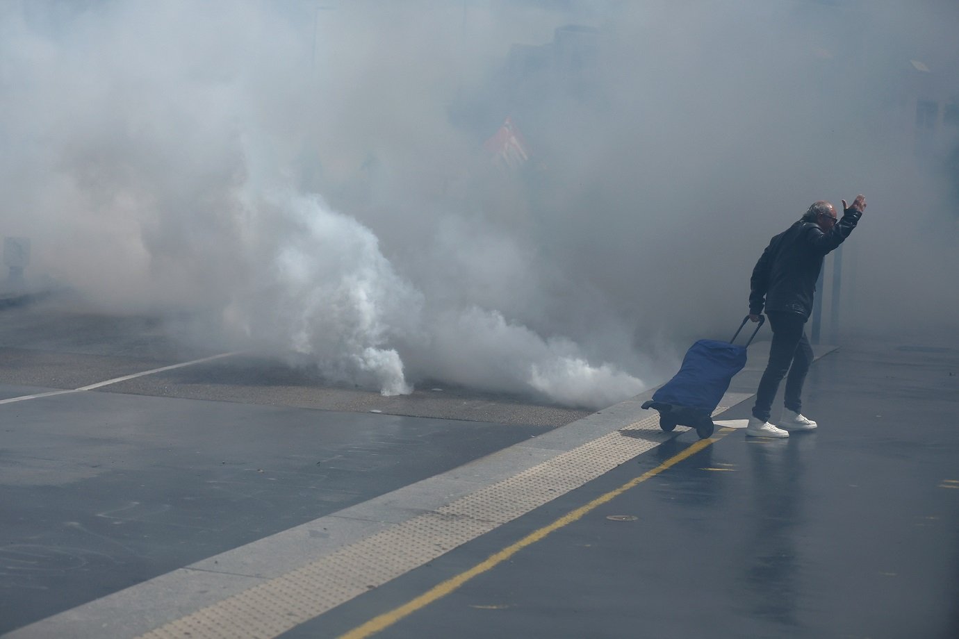 A man pulling a shopping trolley gestures as he walks through clouds of tear gas during a demonstration against the far right, in Nantes, western France, on June 15, 2024. Less than a week after the earthquake of the dissolution, opponents of the far-right are called by trade unions, associations and the left-wing coalition of the "Nouveau Front Populaire" to take to the streets across France after the French President called legislative elections following far-right parties' significant gains in European Parliament elections. (Photo by ROMAIN PERROCHEAU / AFP)