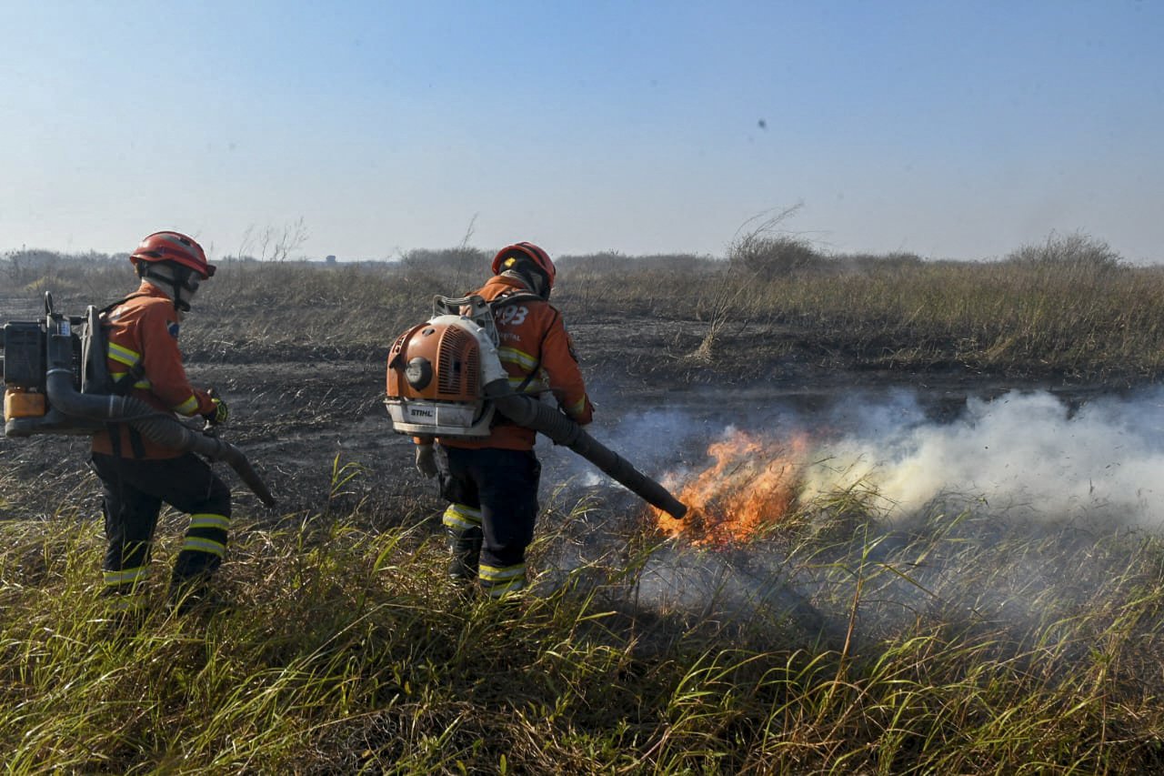 This handout photo released by the Mato Grosso do Sul Government shows firefighters battling to control a wildfire at Pantanal Biome, in the region of Corumba, Mato Grosso do Sul State, Brazil on June 23, 2024. (Photo by Handout / Mato Grosso do Sul State Government / AFP) / RESTRICTED TO EDITORIAL USE - MANDATORY CREDIT 