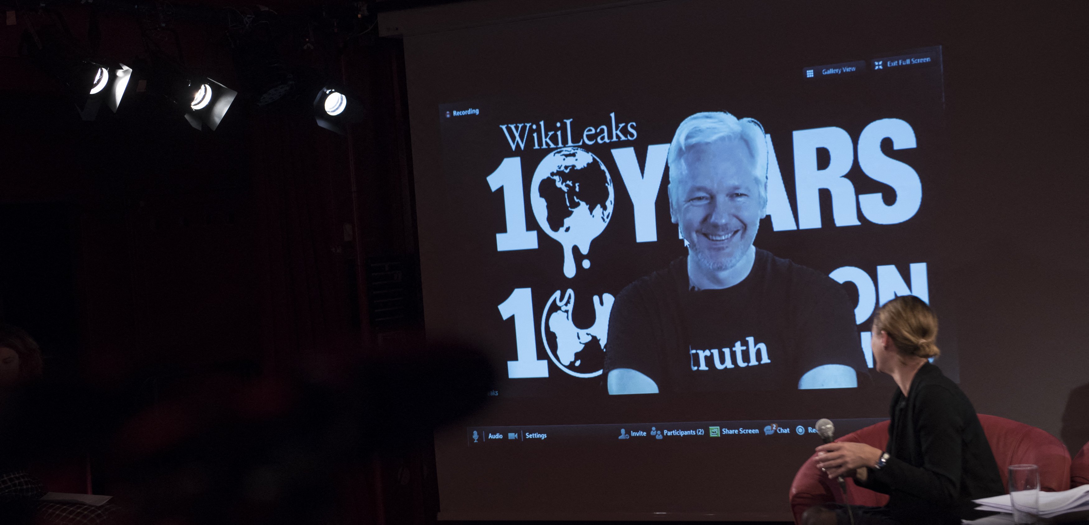 A jornalista britânica e editora da seção WikiLeaks, Sarah Harrison (à direita), olha para uma tela exibindo Julian Assange, fundador da plataforma de vazamentos online WikiLeaks, enquanto ele se dirige aos jornalistas por meio de uma conexão de vídeo ao vivo durante uma coletiva de imprensa no 10º aniversário da plataforma em 4 de outubro de 2016 em Berlim. Julian Assange 'está livre' e foi libertado de uma prisão de segurança máxima em Londres onde estava detido há cinco anos, disse sua organização WikiLeaks em 24 de junho, após chegar a um acordo de confissão nos EUA.