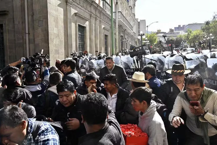 Pessoas se afastam do gás lacrimogêneo disparado por tropas militares em frente ao Palácio Quemado, na Plaza de Armas, em La Paz (AIZAR RALDES/AFP)