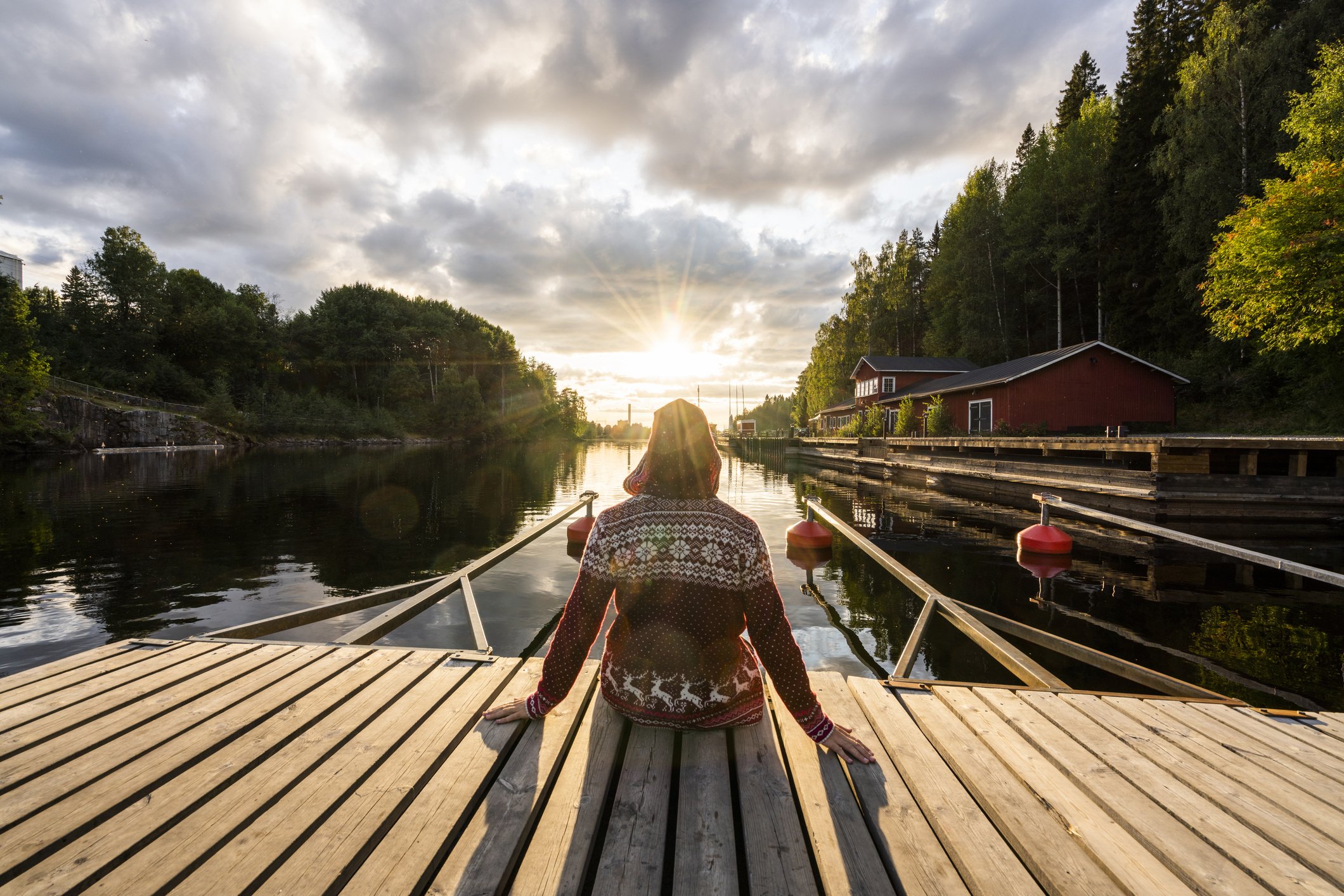 Finland, Kajaani, Man sitting on jetty, watching sunset, rear view