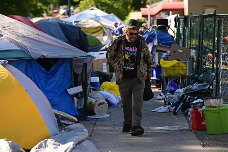 Homem passa por acampamentos de moradores de rua em Denver