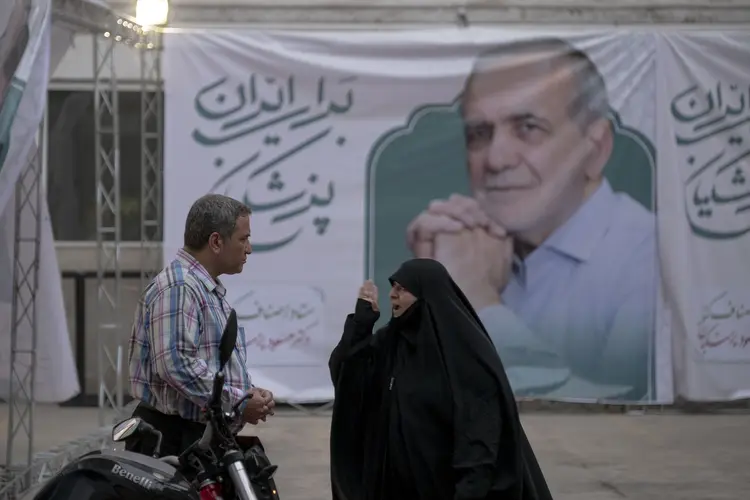 Mulher protesta em frente à faixa de apoio a Pezeshkian