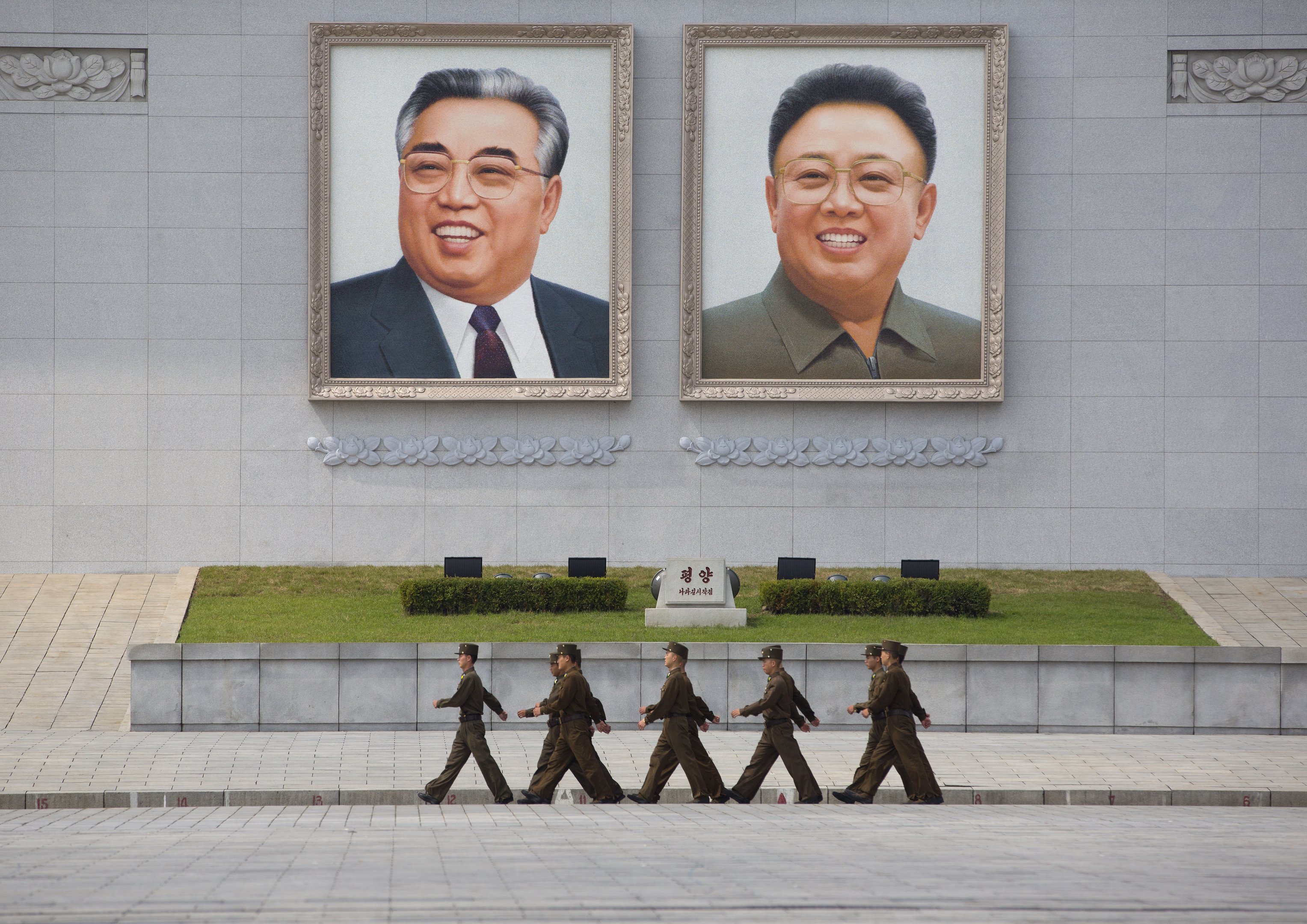 PYONGYANG, NORTH KOREA - SEPTEMBER 09: North korean people army soldiers passing in front of kim il sung and kim jong il giant portraits on kim il sung square, pyongyang, North Korea on September 9, 2012 in Pyongyang, North Korea.