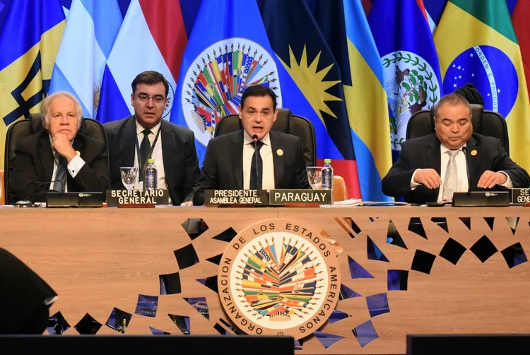 O chanceler paraguaio e presidente da Assembleia Geral da OEA, Rubén Ramírez Lezcano (C), discursa ao lado do secretário-geral da Organização dos Estados Americanos (OEA), o uruguaio Luis Almagro (E), e do secretário-geral adjunto, o belizenho Néstor Méndez, durante o 54º Período Ordinário de Sessões no Paraguai, em 27 de junho de 2024 (AFP/AFP)