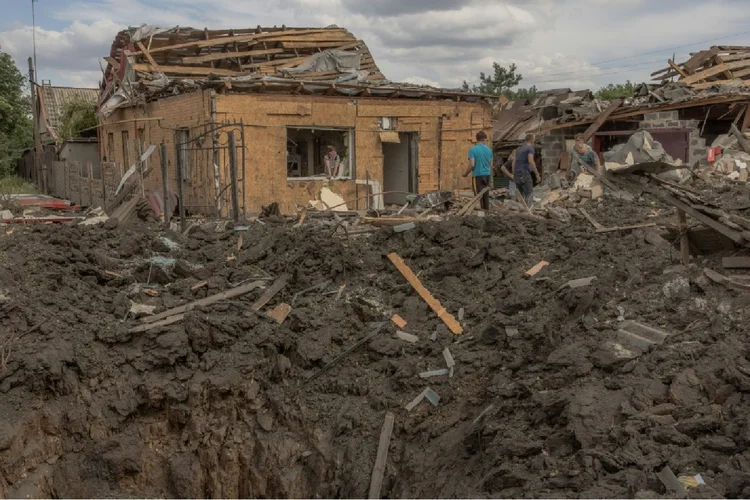 Moradores limpam escombros ao lado de casas fortemente danificadas após bombardeio em Pokrovsk, região leste de Donetsk, em 24 de junho de 2024, em meio à invasão russa na Ucrânia (Agence France-Presse/AFP)