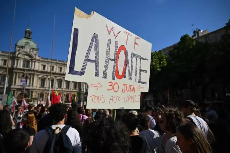 Um manifestante segura um cartaz que diz 'Vergonha! Todos às urnas em 30 de junho' durante uma manifestação contra o partido francês de extrema direita 'Rassemblement National' (RN) em Marselha, sul da França.  (Nicolas TUCAT/AFP)