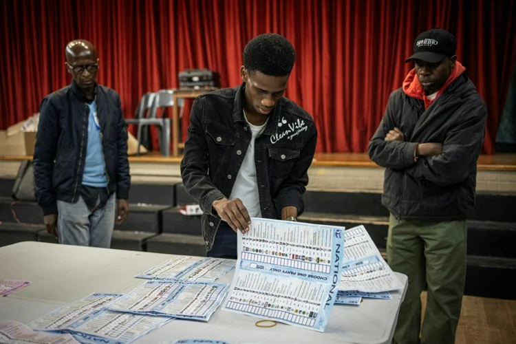 A comissão eleitoral conta os votos em uma assembleia de voto em Joanesburgo, em 29 de maio de 2024, durante as eleições gerais sul-africanas (AFP/AFP)