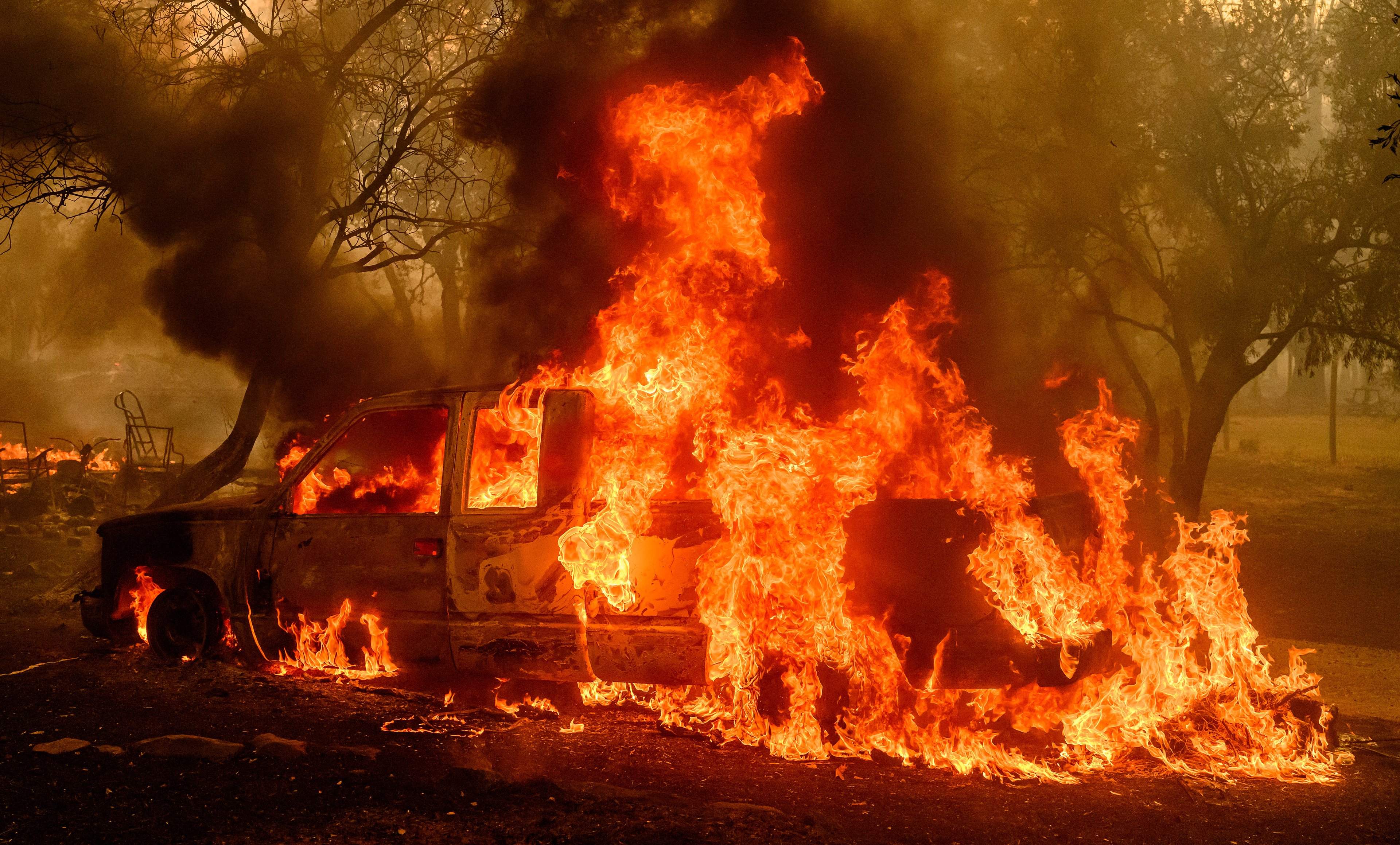 A car burns as flames engulf a home nearby during the Thompson fire in Oroville, California on July 2, 2024. A heatwave is sending temperatures soaring resulting in red flag fire warnings throughout the state. (Photo by JOSH EDELSON / AFP)
