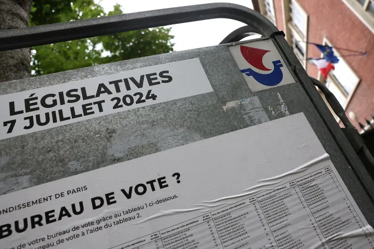 Uma placa indicando a localização dos centros de votação está do lado de fora de um centro de votação em Paris, em 3 de julho de 2024, antes do segundo turno das eleições legislativas da França, agendado para 7 de julho (Emmanuel Dunnand/AFP)