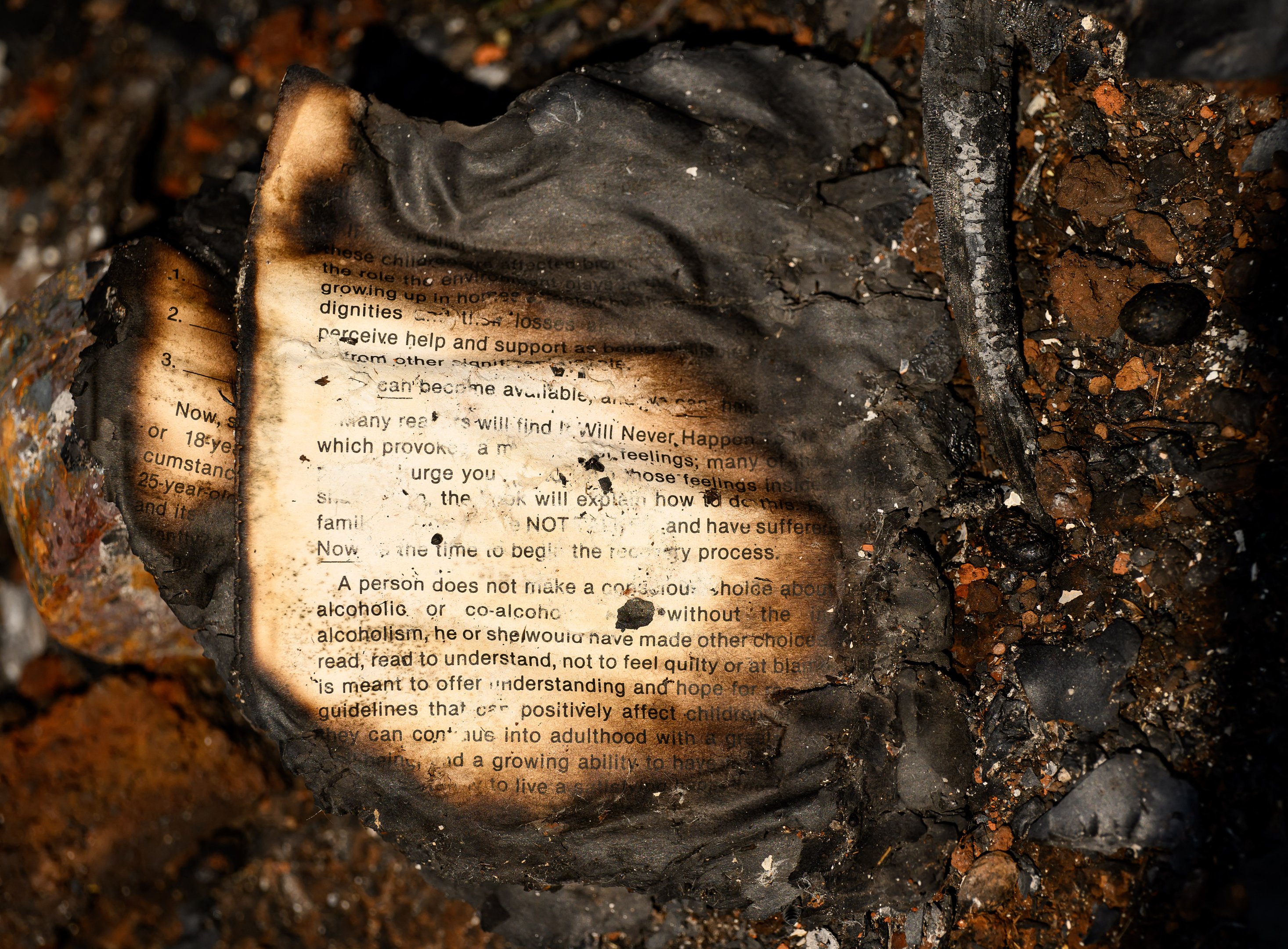 A partially burned book is seen at the remains of a burned home during the Thompson fire in Oroville, California on July 3, 2024. A heatwave is sending temperatures soaring resulting in red flag fire warnings throughout the state. (Photo by JOSH EDELSON / AFP)