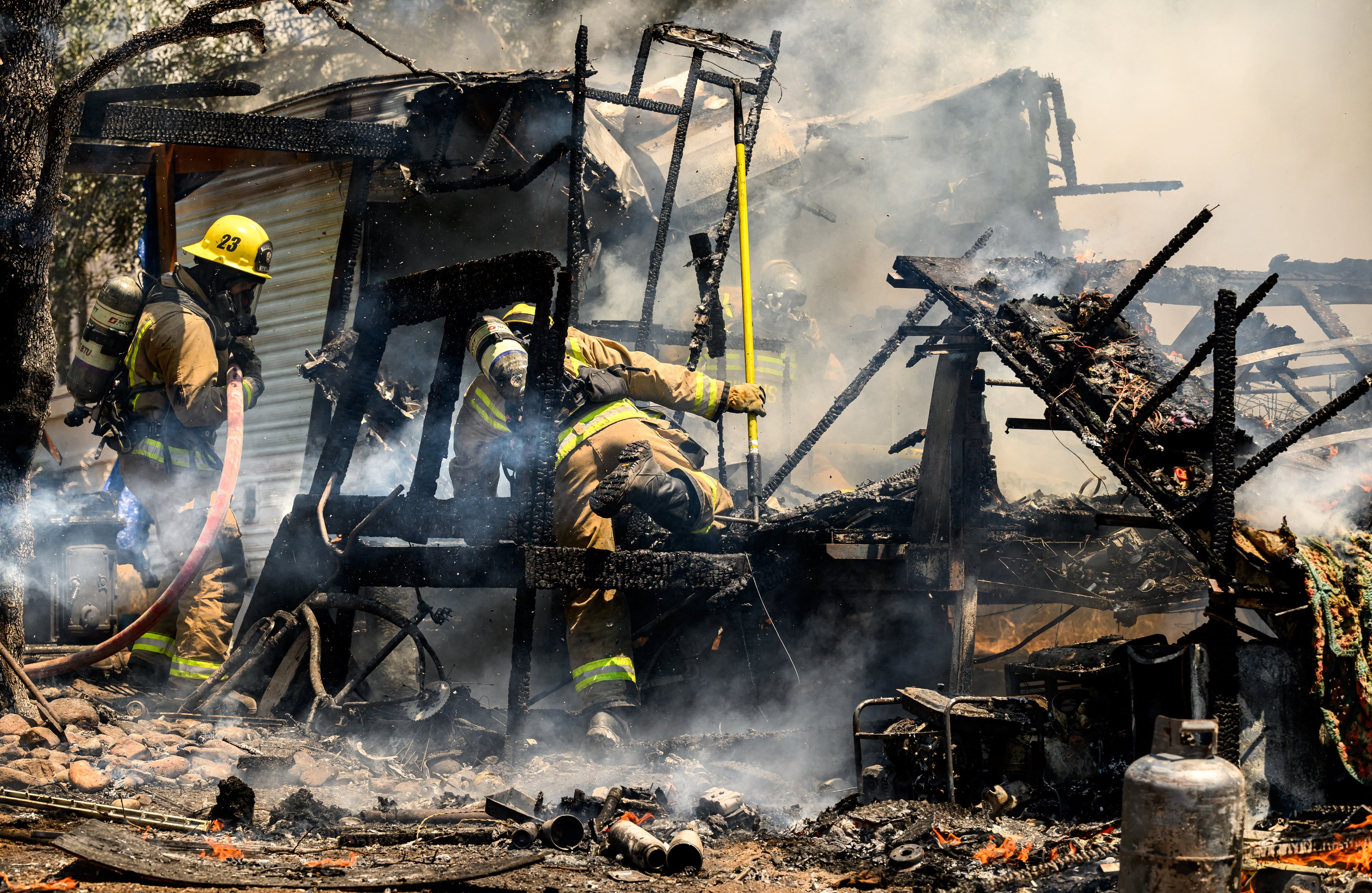Firefighters knock down a structure fire that ignited from a burning generator and briefly spread to a small spot fire at a home in Oroville, California on July 03, 2024. A heatwave is sending temperatures soaring resulting in red flag fire warnings throughout the state. (Photo by JOSH EDELSON / AFP)