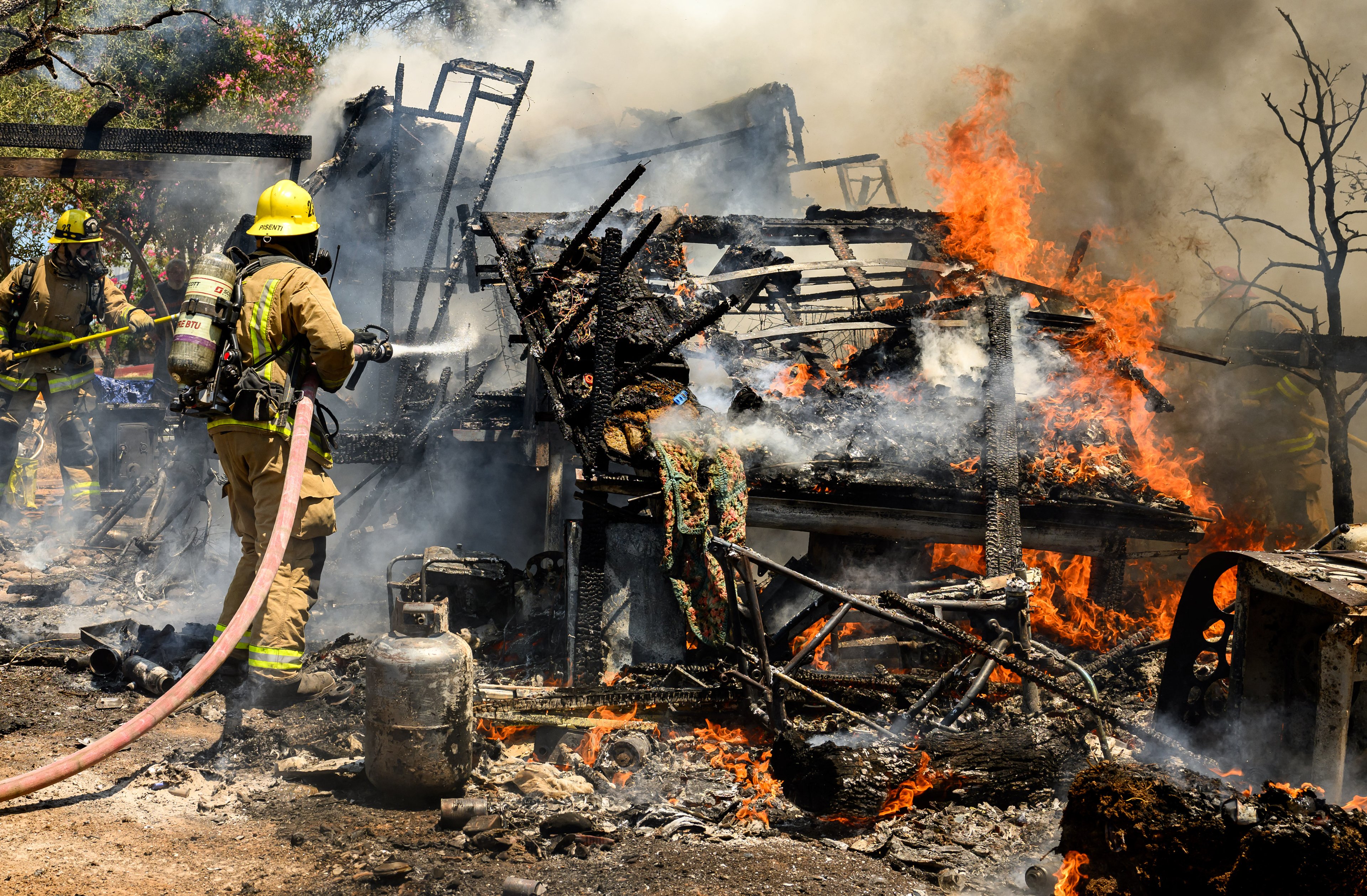 Firefighters knock down a structure fire that ignited from a burning generator and briefly spread to a small spot fire at a home during the Thompson fire in Oroville, California on July 3, 2024. A heatwave is sending temperatures soaring resulting in red flag fire warnings throughout the state. (Photo by JOSH EDELSON / AFP)