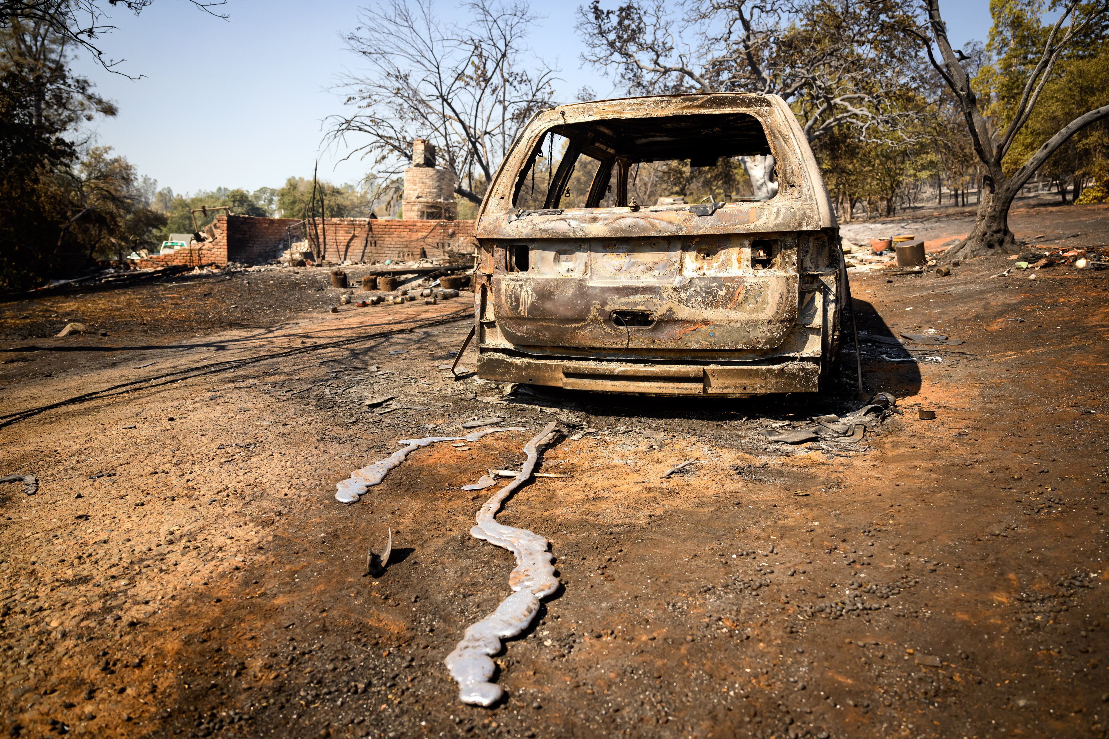 A burned vehicles leaves a trail of melted metal down a driveway as the Thompson fire continues to burn in Oroville, California on July 03, 2024. A heatwave is sending temperatures soaring resulting in red flag fire warnings throughout the state. (Photo by JOSH EDELSON / AFP)