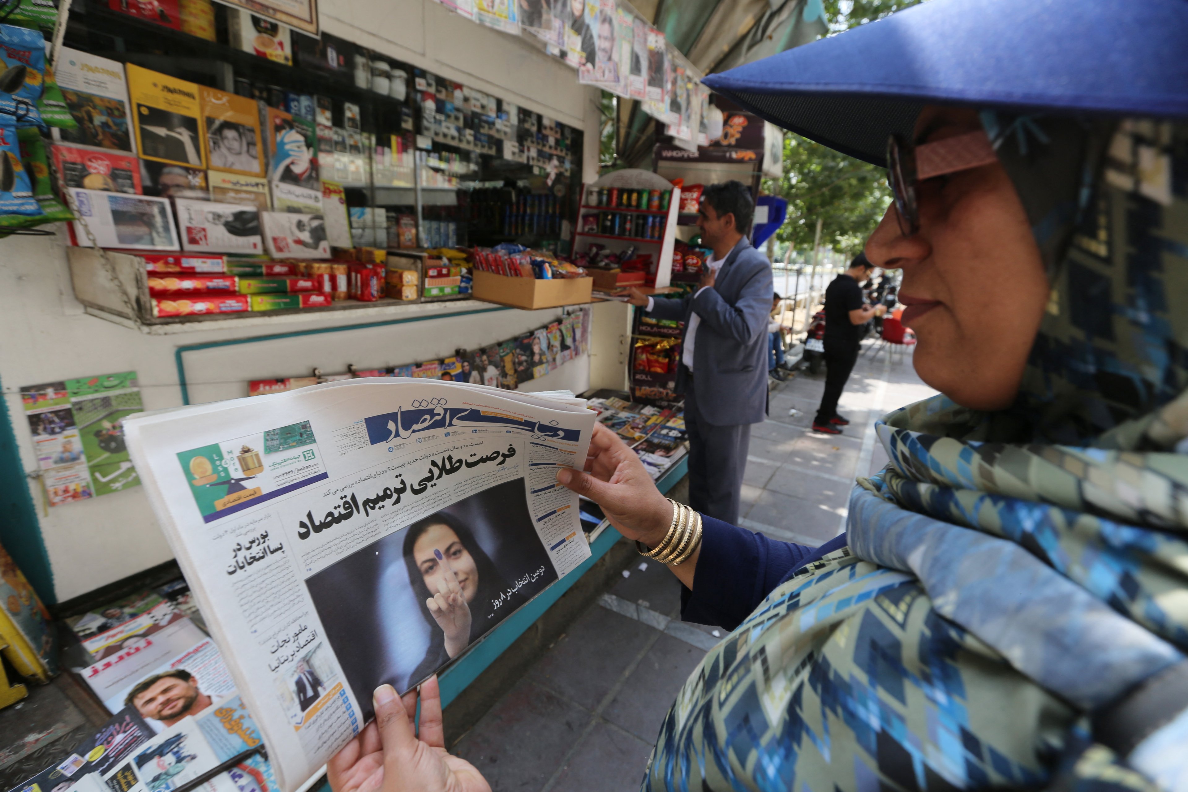 Uma mulher iraniana olha para a manchete de um jornal em uma banca de rua em Teerã em 6 de julho de 2024, um dia após o país realizar eleições presidenciais