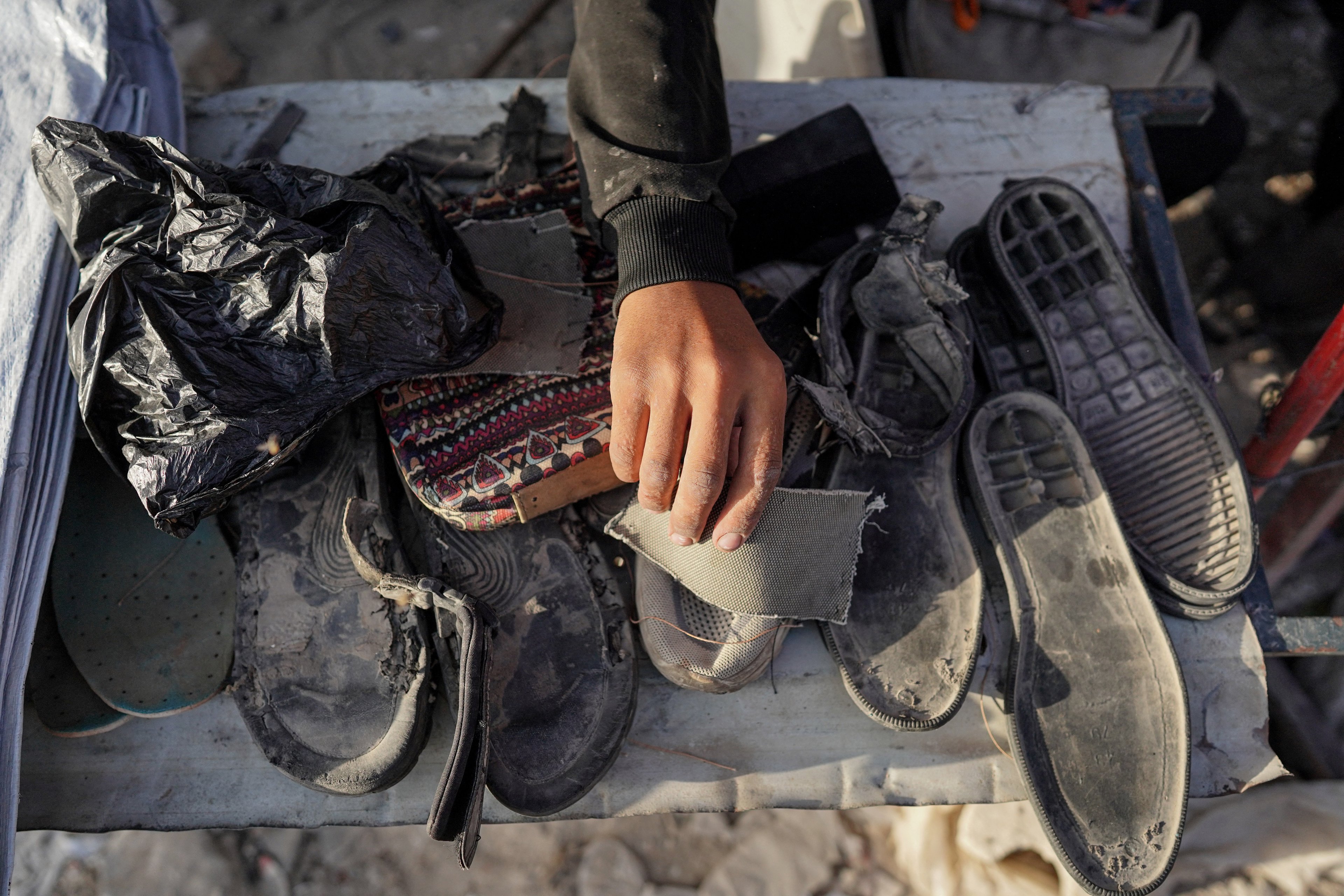 Um sapateiro palestino repara sapatos usando materiais reciclados de sapatos velhos na cidade de Khan Yunis, no sul da Faixa de Gaza, em 5 de julho de 2024.