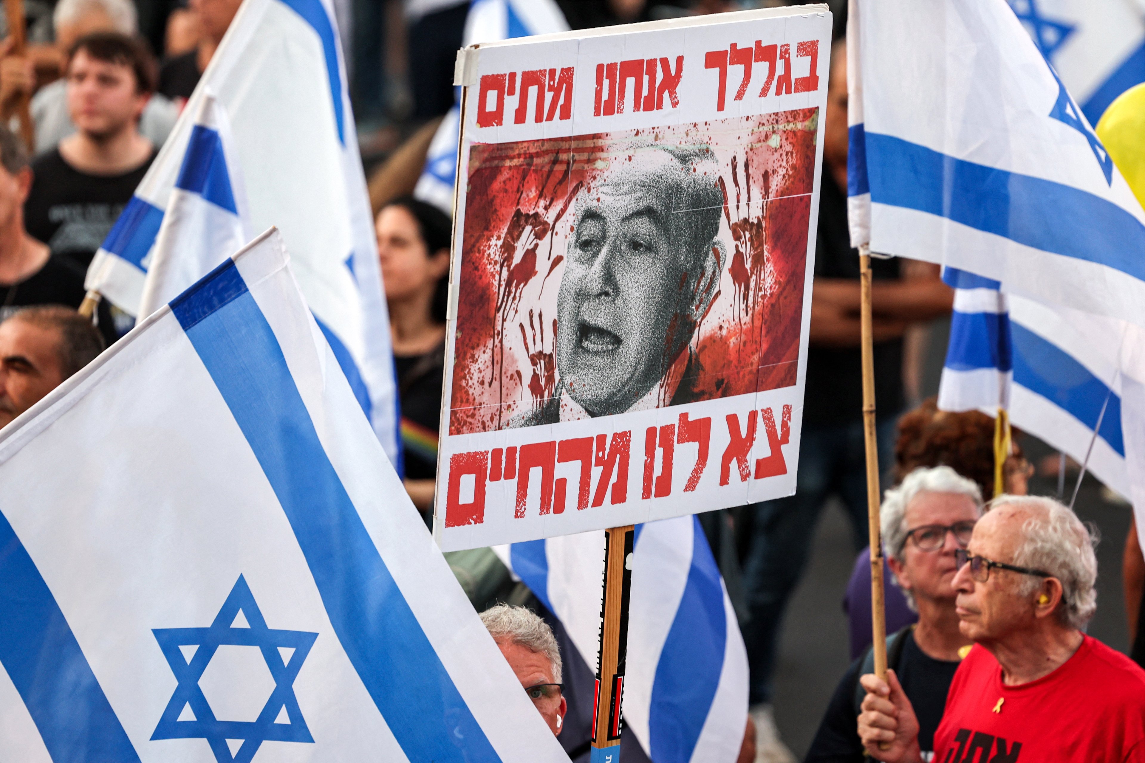 Um manifestante segura um cartaz denunciando o primeiro-ministro israelense Benjamin Netanyahu durante uma manifestação de ativistas de esquerda contra o governo israelense em Tel Aviv, em 6 de julho de 2024, em meio ao conflito contínuo na Faixa de Gaza entre Israel e o Hamas. (Foto de JACK GUEZ / AFP)