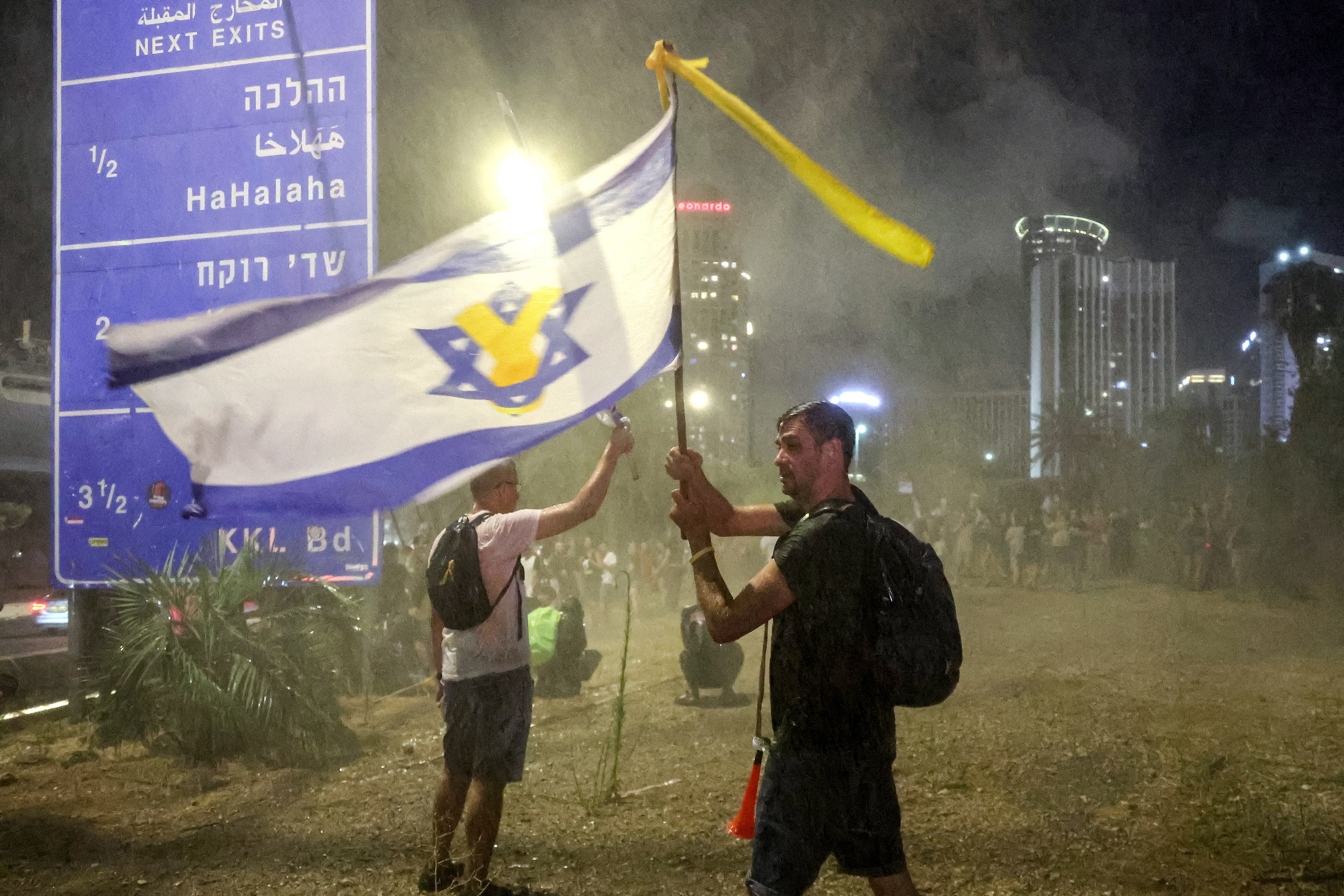 Manifestantes de esquerda são atingidos por canhões de água das forças de segurança israelenses para dispersá-los às margens de uma manifestação antigovernamental em Tel Aviv, em 6 de julho de 2024, em meio ao conflito contínuo na Faixa de Gaza entre Israel e o Hamas. (Foto de JACK GUEZ / AFP)