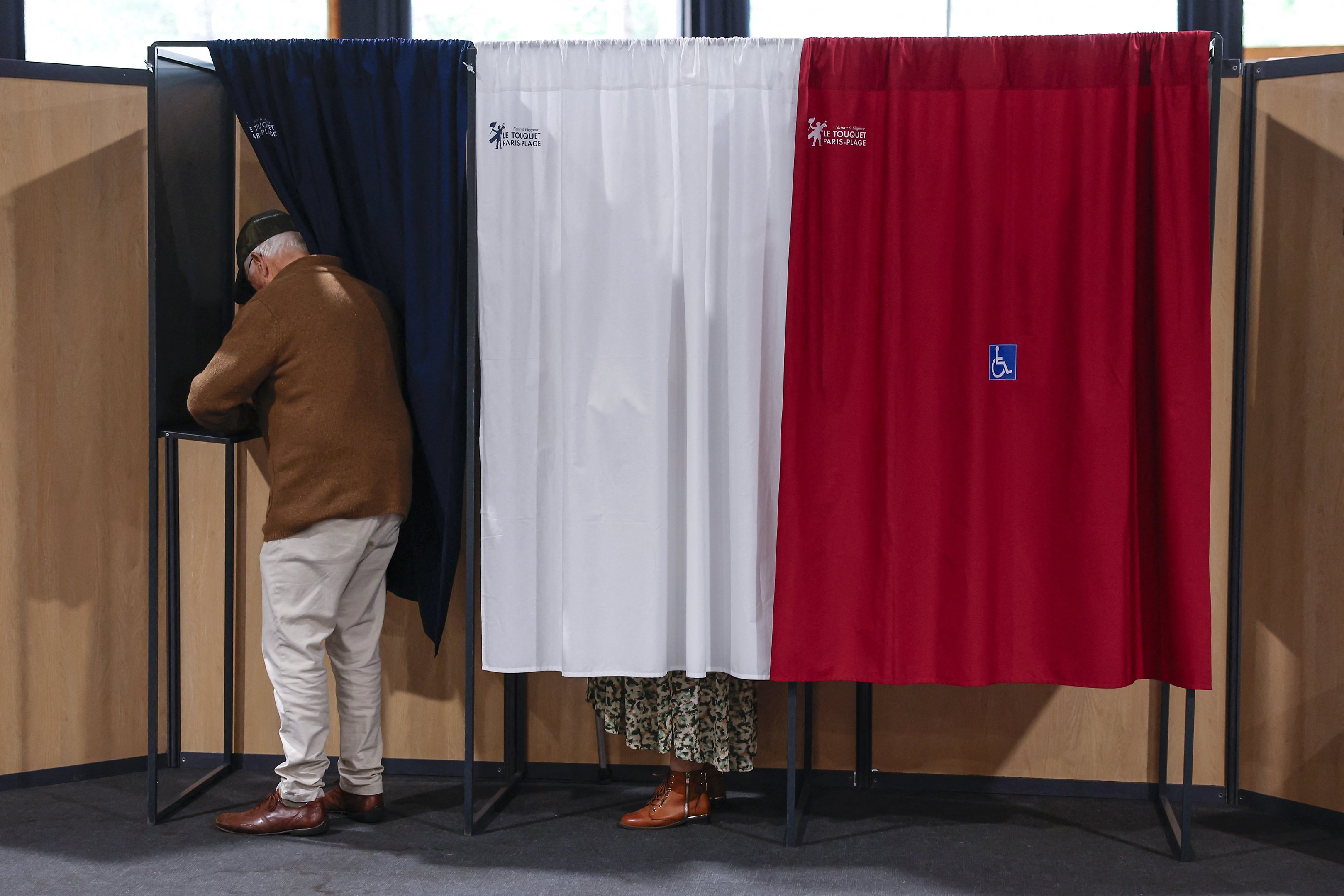 Um homem entra em uma cabine de votação para votar no segundo turno das eleições legislativas da França em um local de votação em Le Touquet, norte da França, em 7 de julho de 2024. A França vota nas eleições legislativas em 7 de julho de 2024, que serão decisivas para determinar seu futuro político e podem ver a extrema direita se tornar o maior partido no parlamento pela primeira vez