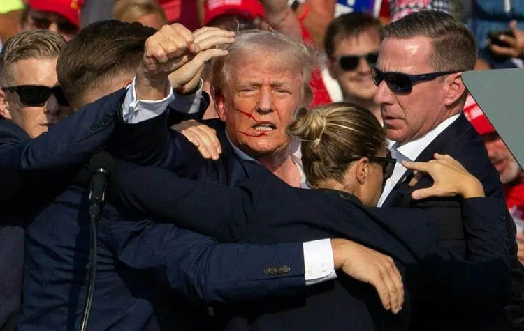 O candidato republicano Donald Trump é visto com sangue no rosto, cercado por agentes do Serviço Secreto enquanto é retirado do palco em um evento de campanha na Butler Farm Show Inc., em Butler, Pensilvânia, em 13 de julho de 2024 (Rebecca Droke/AFP)
