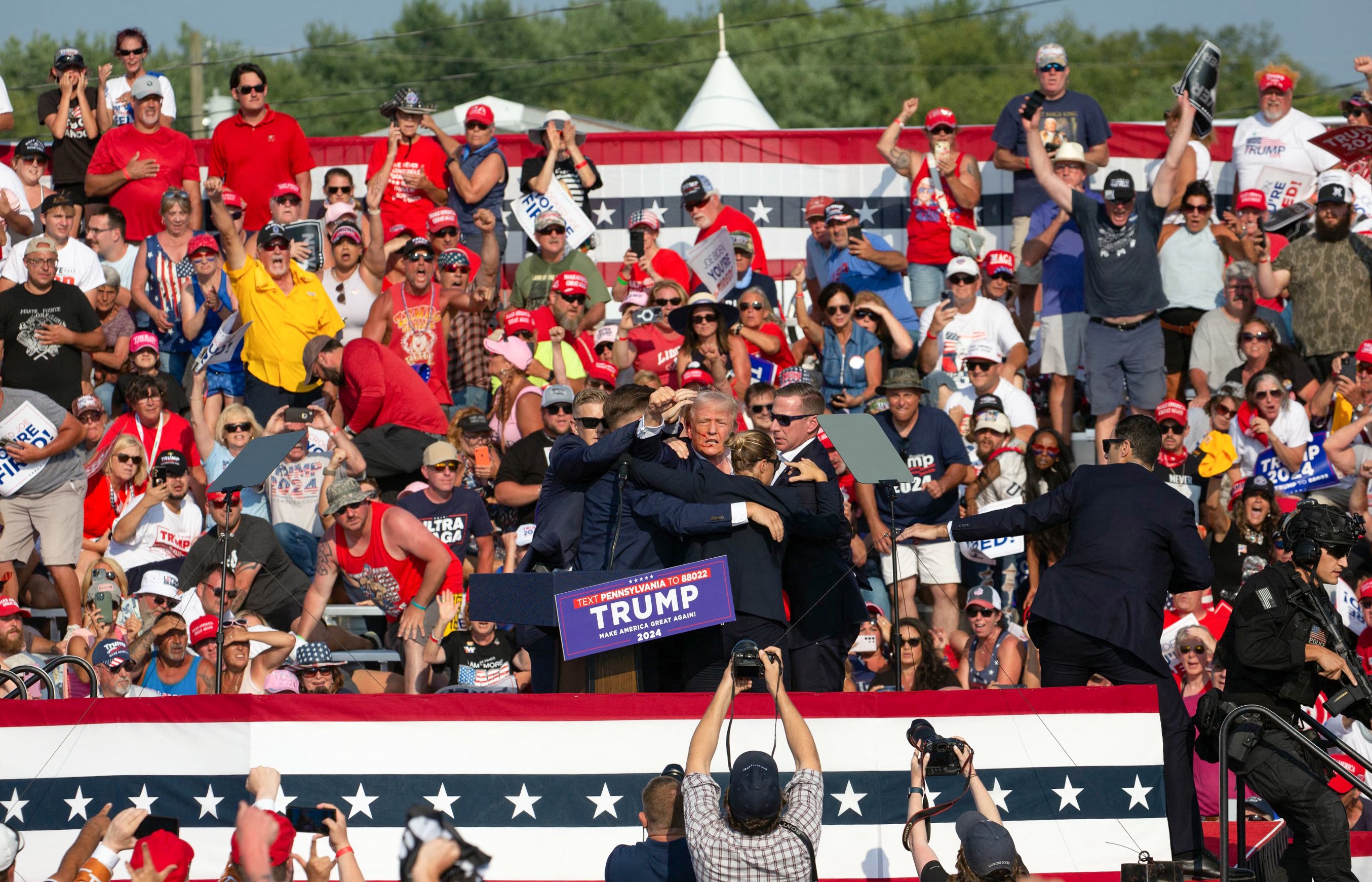 O candidato republicano Donald Trump é visto com sangue no rosto, cercado por agentes do Serviço Secreto, enquanto é retirado do palco em um evento de campanha na Butler Farm Show Inc., em Butler, Pensilvânia, em 13 de julho de 2024.