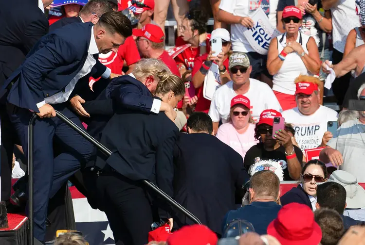 O candidato republicano Donald Trump é visto com sangue no rosto, cercado por agentes do Serviço Secreto, enquanto é retirado do palco em um evento de campanha na Butler Farm Show Inc., em Butler, Pensilvânia, em 13 de julho de 2024 (Anna Moneymaker/AFP)