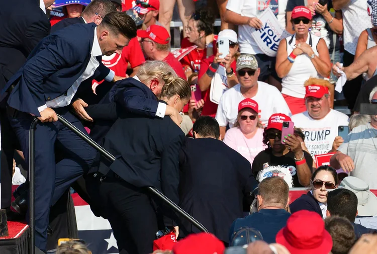 O candidato republicano Donald Trump é visto com sangue no rosto, cercado por agentes do Serviço Secreto, enquanto é retirado do palco em um evento de campanha na Butler Farm Show Inc., em Butler, Pensilvânia, em 13 de julho de 2024 (Anna Moneymaker/AFP)