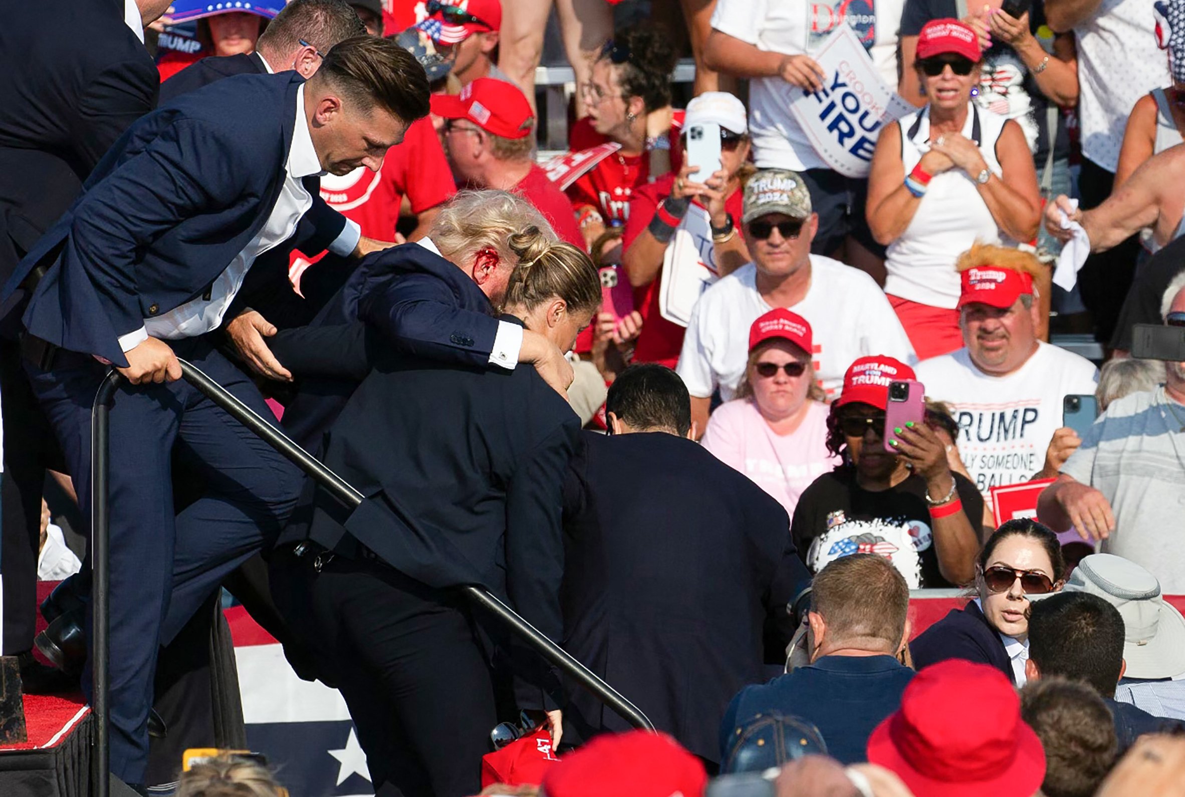 O candidato republicano Donald Trump é visto com sangue no rosto, cercado por agentes do Serviço Secreto, enquanto é retirado do palco em um evento de campanha na Butler Farm Show Inc., em Butler, Pensilvânia, em 13 de julho de 2024