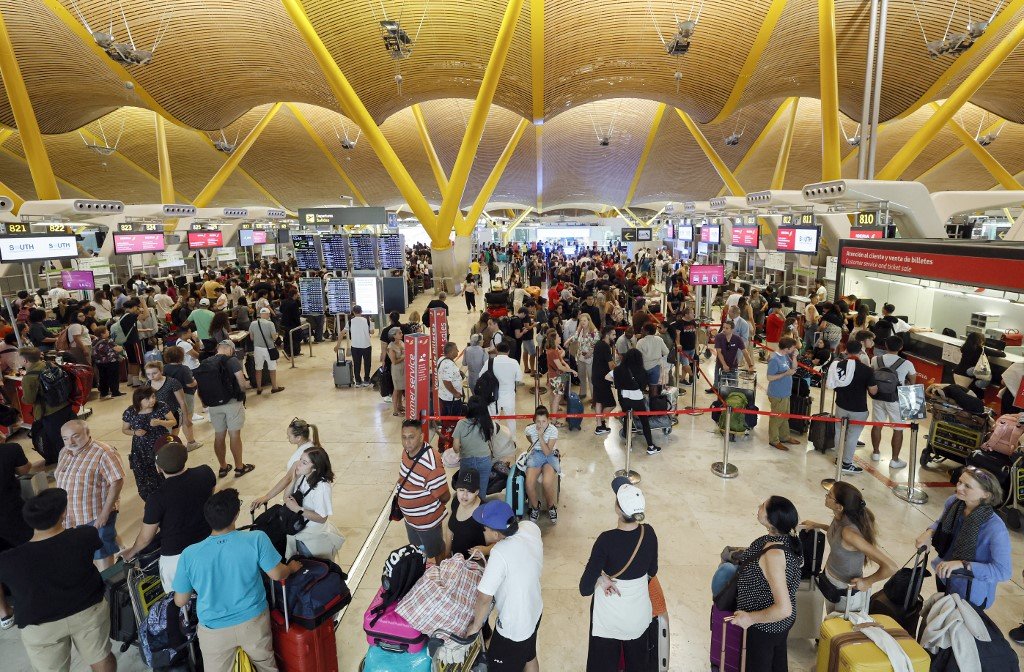 Passengers stand in terminal 4 of Adolfo Suarez MadridBarajas Airport in Madrid on July 19, 2024, amid massive global IT outage. Airlines, banks, TV channels and other business across the globe were scrambling to deal with one of the biggest IT crashes in recent years on July 19, 2024, caused by an update to an antivirus program. (Photo by OSCAR DEL POZO / AFP)