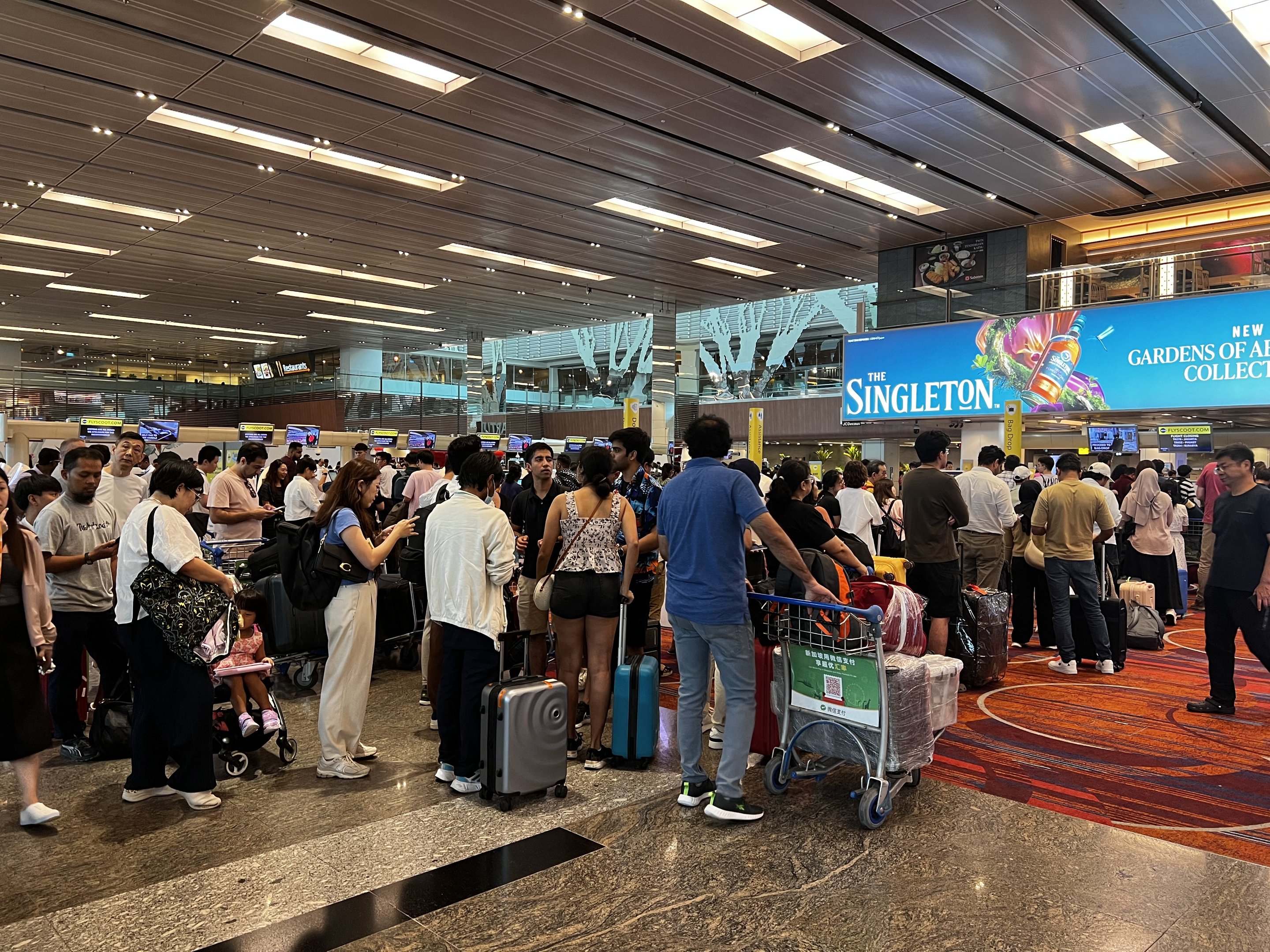Passengers formed a long queues at Singapore Airport due to major IT outage in Singapore on July 19, 2024. A major outage wrought havoc on computer systems worldwide, grounding flights in the United States, derailing television broadcasts in the UK and impacting telecommunications in Australia. (Photo by Roslan RAHMAN / AFP)