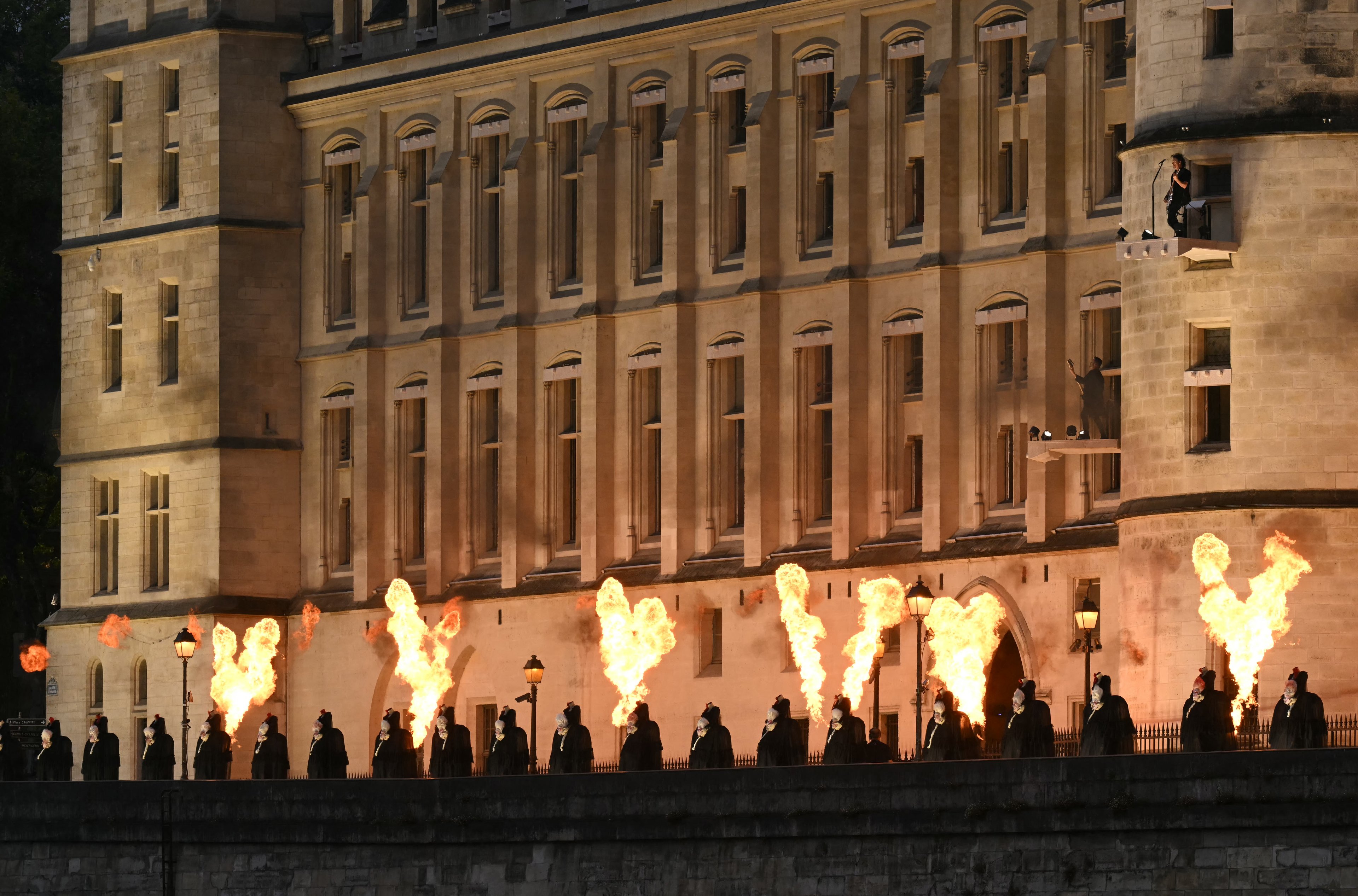 Figuras sem cabeça representando a rainha Maria Antonieta do século XVIII se alinham com shows de fogo ao longo da margem do rio Sena, do lado de fora da Conciergerie, onde a rainha foi mantida em cativeiro durante a Revolução Francesa, durante a cerimônia de abertura das Olimpíadas de Paris 2024
