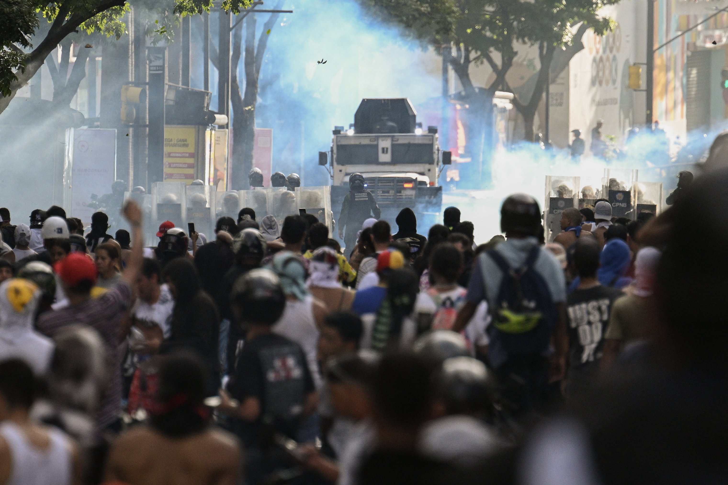 Manifestantes entram em confronto com a polícia perto de um carro blindado da polícia durante um protesto contra o presidente venezuelano Nicolás Maduro em Caracas.