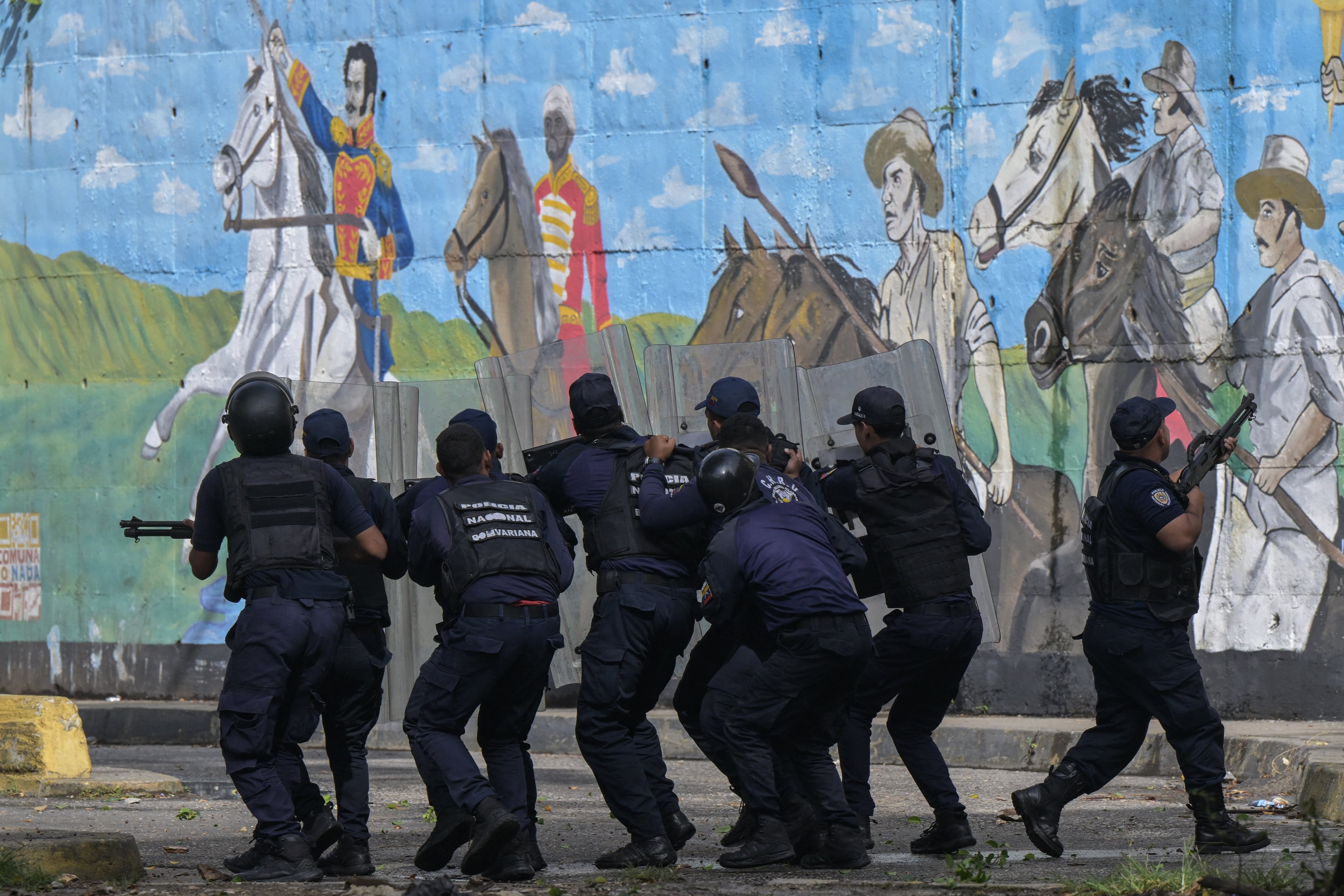 Policiais protegem-se dos manifestantes durante um protesto contra o governo do presidente Nicolás Maduro em Caracas.