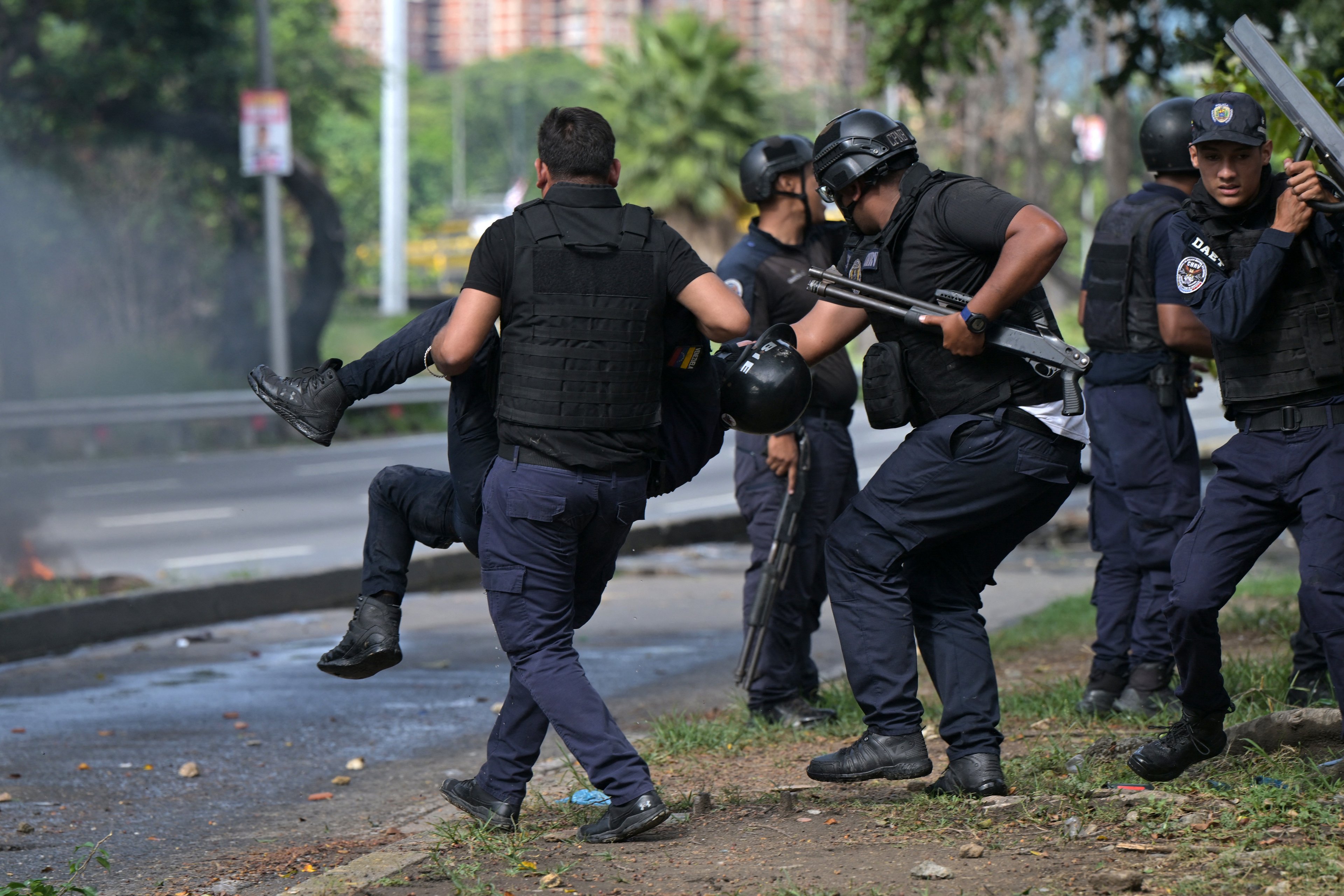 Um policial carrega um colega ferido durante um protesto contra o governo do presidente Nicolás Maduro em Caracas.