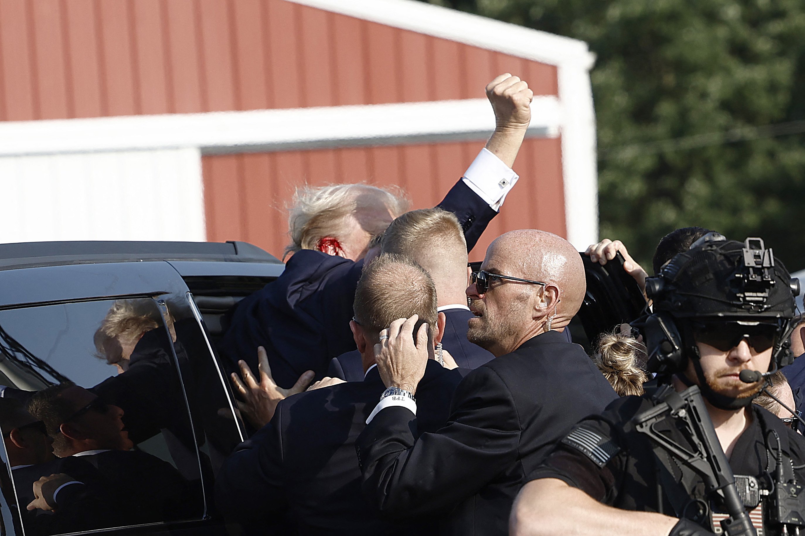 O candidato republicano à presidência e ex-presidente Donald Trump ergue o punho enquanto é rapidamente conduzido para o carro após um incidente em um comício em 13 de julho de 2024, em Butler, Pensilvânia.