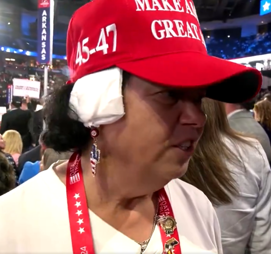 Eleitora de Donald Trump com a orelha enfaixada e boné com a frase "Faça a América Grandiosa de Novo"