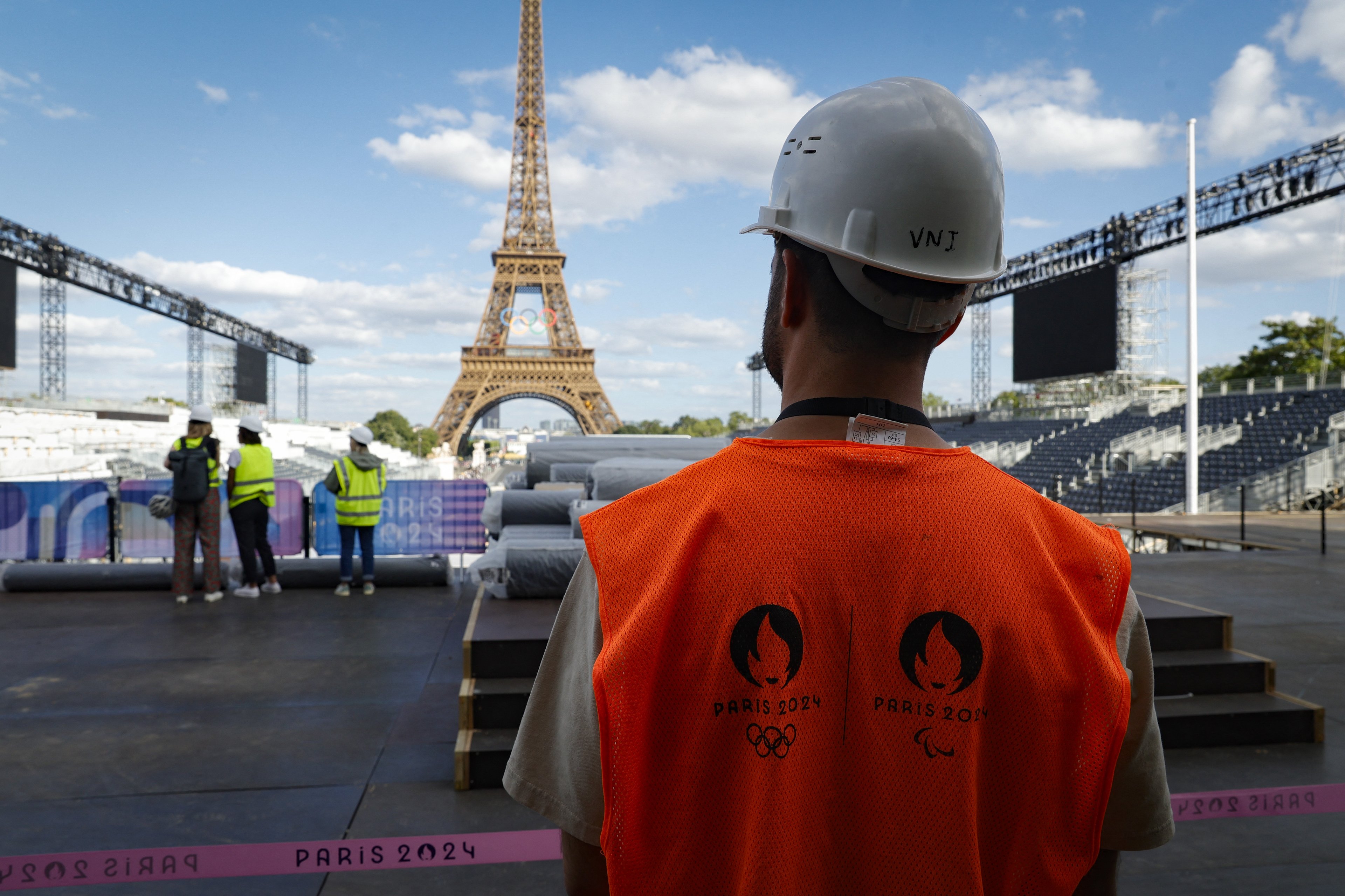 A man wearing a bib with Paris 2024 jersey the construction site of Parc des Champions (Champion's Park) at the foot of the Eiffel Tower at the Trocadero for the upcoming Paris 2024 Olympic Games, in Paris on July 4, 2024. The Parc des Champions is a celebration site, which will be accessible for the public to see the Olympic medallists a day after their exploits. (Photo by Geoffroy VAN DER HASSELT / AFP) (Photo by GEOFFROY VAN DER HASSELT/AFP via Getty Images)