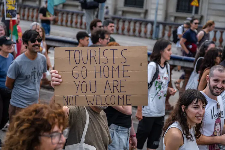 Em Barcelona, manifestante segura cartaz pedindo para turistas voltarem para suas casas. (SOPA Images/Getty Images)