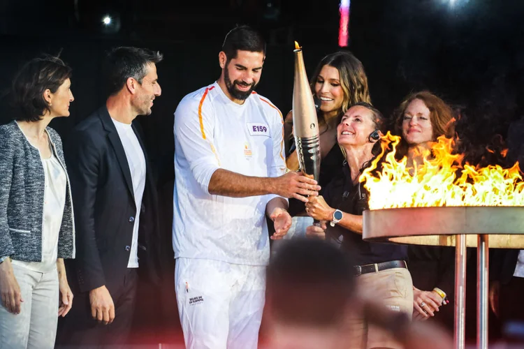 Nikola Karabatic, último portador da tocha carregando a chama olímpica com a tocha nas costas, após o acendimento do caldeirão da chama olímpica na Place de la Republique (Maeva Destombes / Hans Lucas / Hans Lucas via AFP) (Photo by MAEVA DESTOMBE/Getty Images)