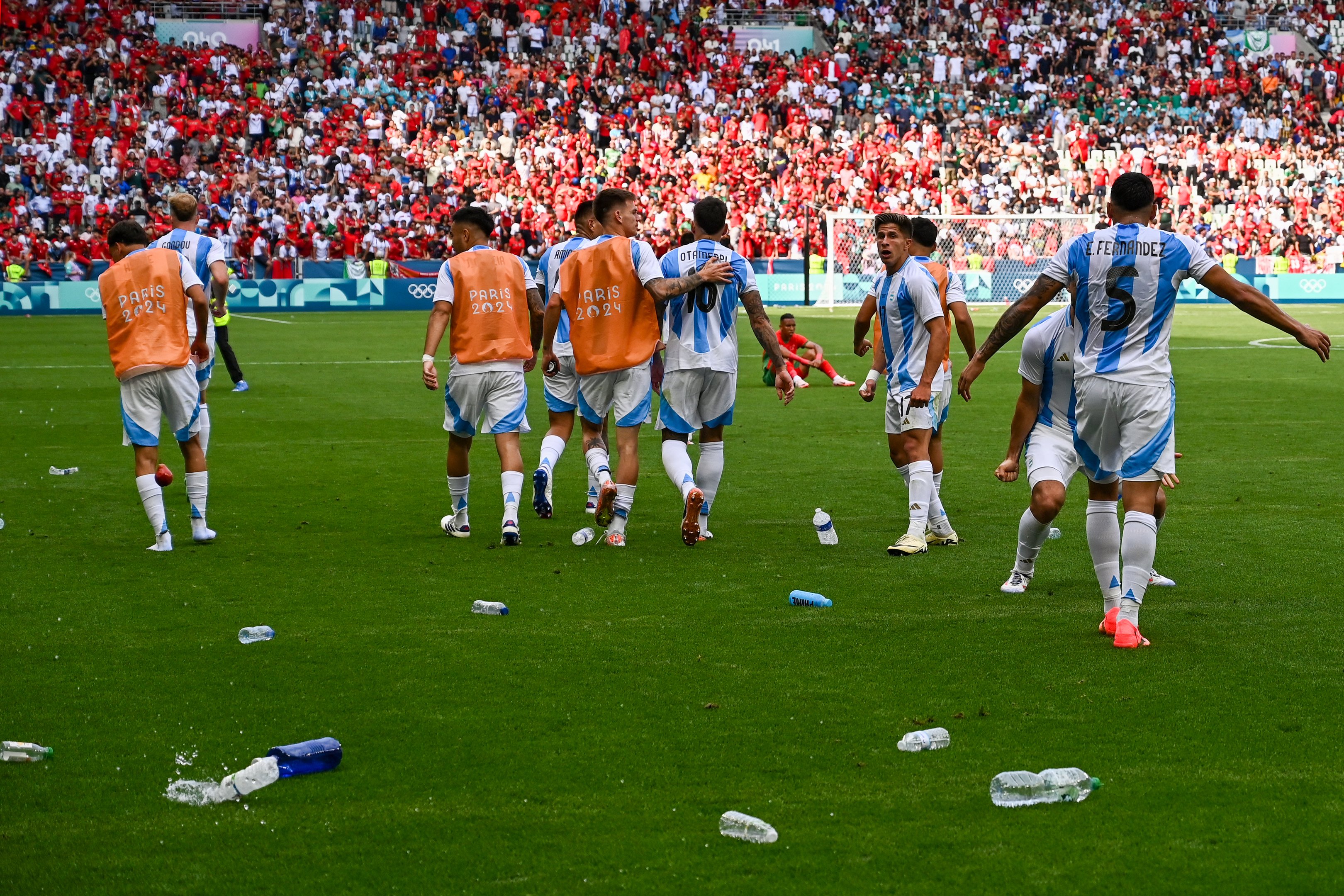 O atacante argentino nº 17 Giuliano Simeone (2ºD) observa enquanto garrafas de água jogadas pelos torcedores do Marrocos enchem o campo
