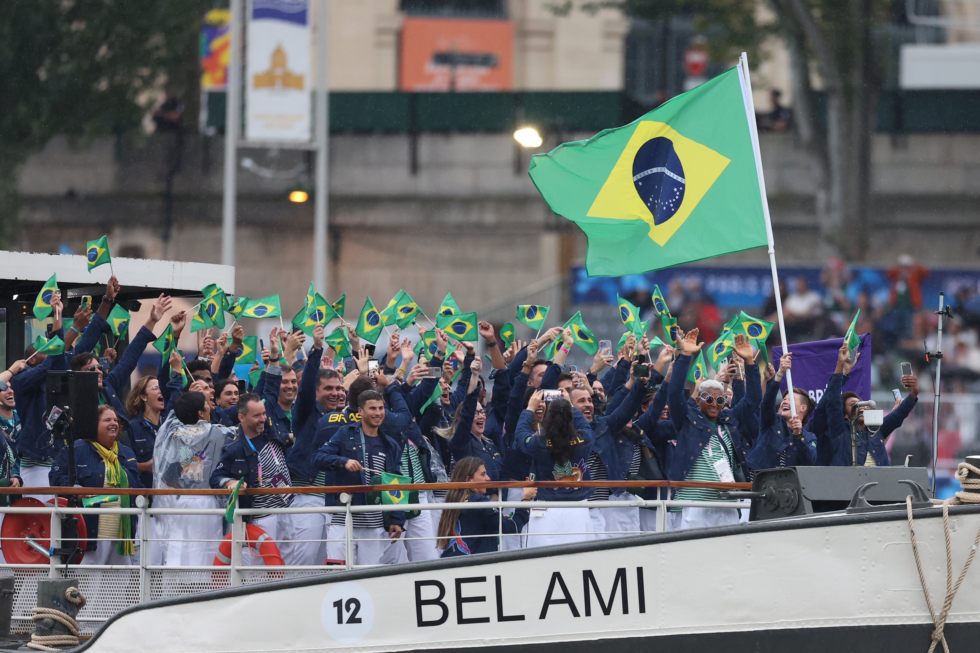 Isaquias Guimarães Queiroz e Raquel Kochhann, porta-bandeiras do Time Brasil, agitam sua bandeira enquanto são vistos em um barco no Rio Sena durante a cerimônia de abertura dos Jogos Olímpicos Paris 2024